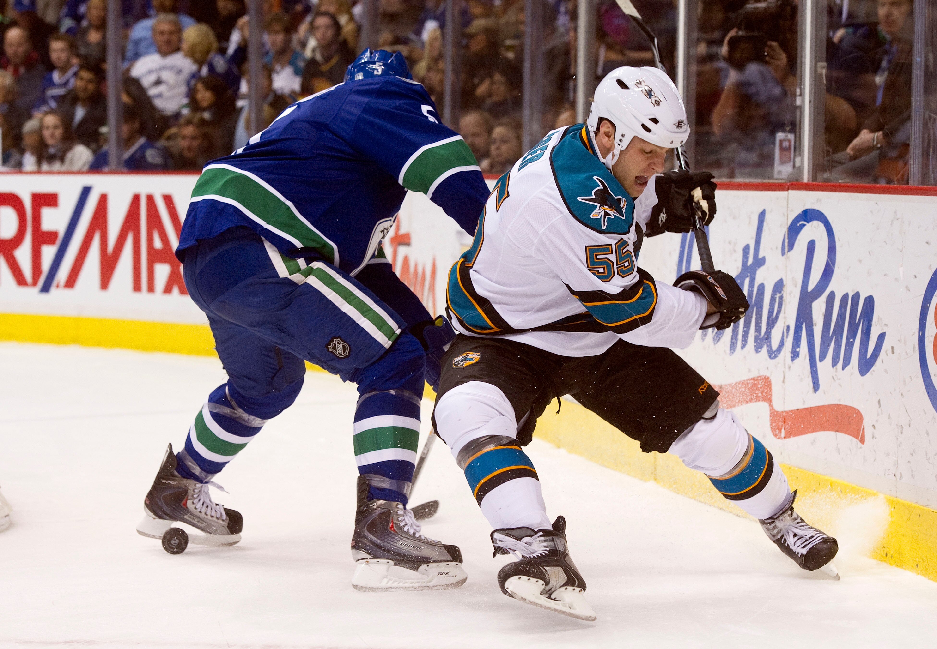 VANCOUVER, CANADA - JANUARY 20:  Ben Eager #55 of the San Jose Sharks is bumped off the puck by Christian Ehrhoff #5 of the Vancouver Canucks during the first period in NHL action on January 20, 2011 at Rogers Arena in Vancouver, BC, Canada.  (Photo by Ri