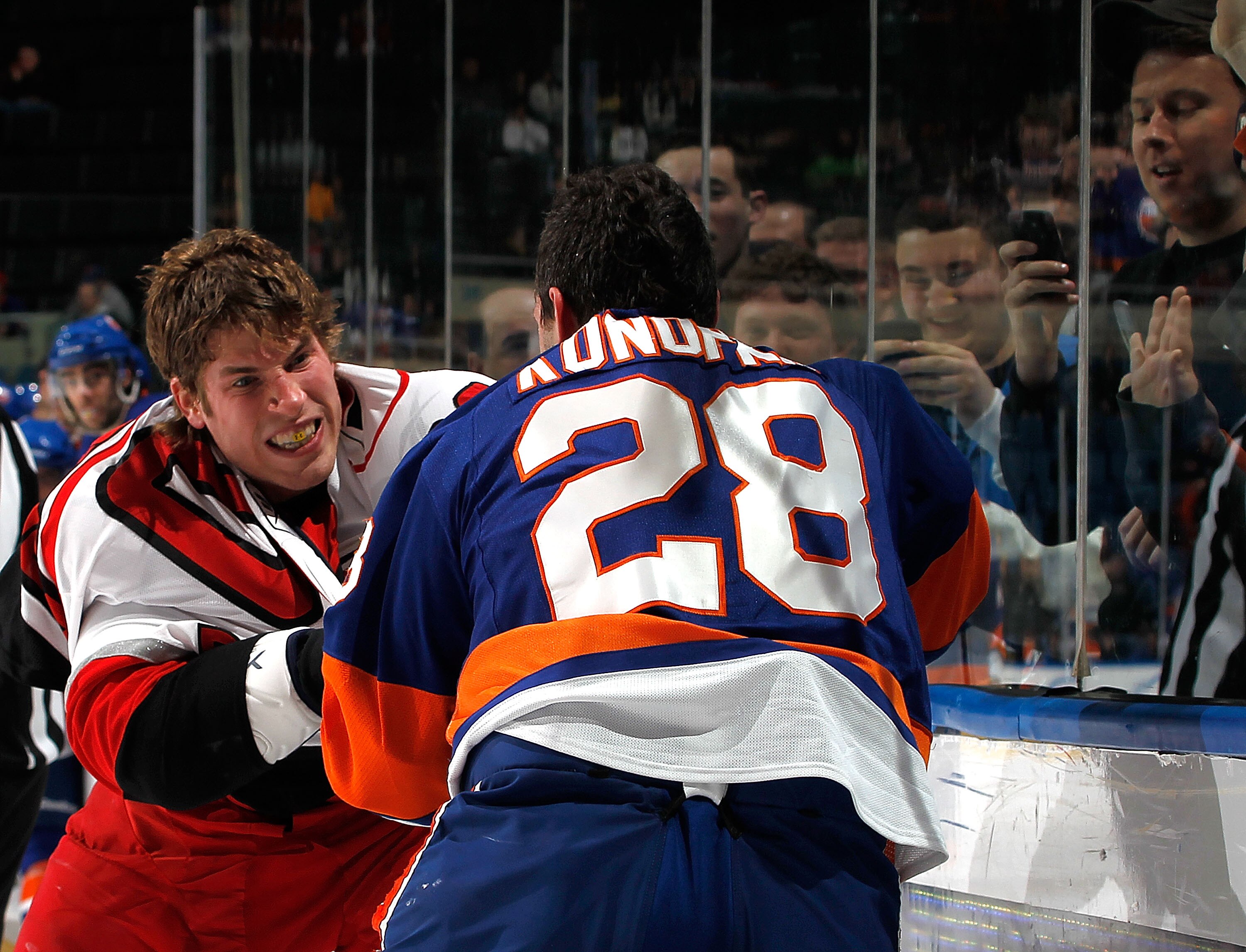 UNIONDALE, NY - JANUARY 26:  Fans behind the glass take photos with their cell phones as Troy Bodie #20 of the Carolina Hurricanes fights with Zenon Konopka #28 of the New York Islanders during the second period of an NHL hockey game at the Nassau Coliseu