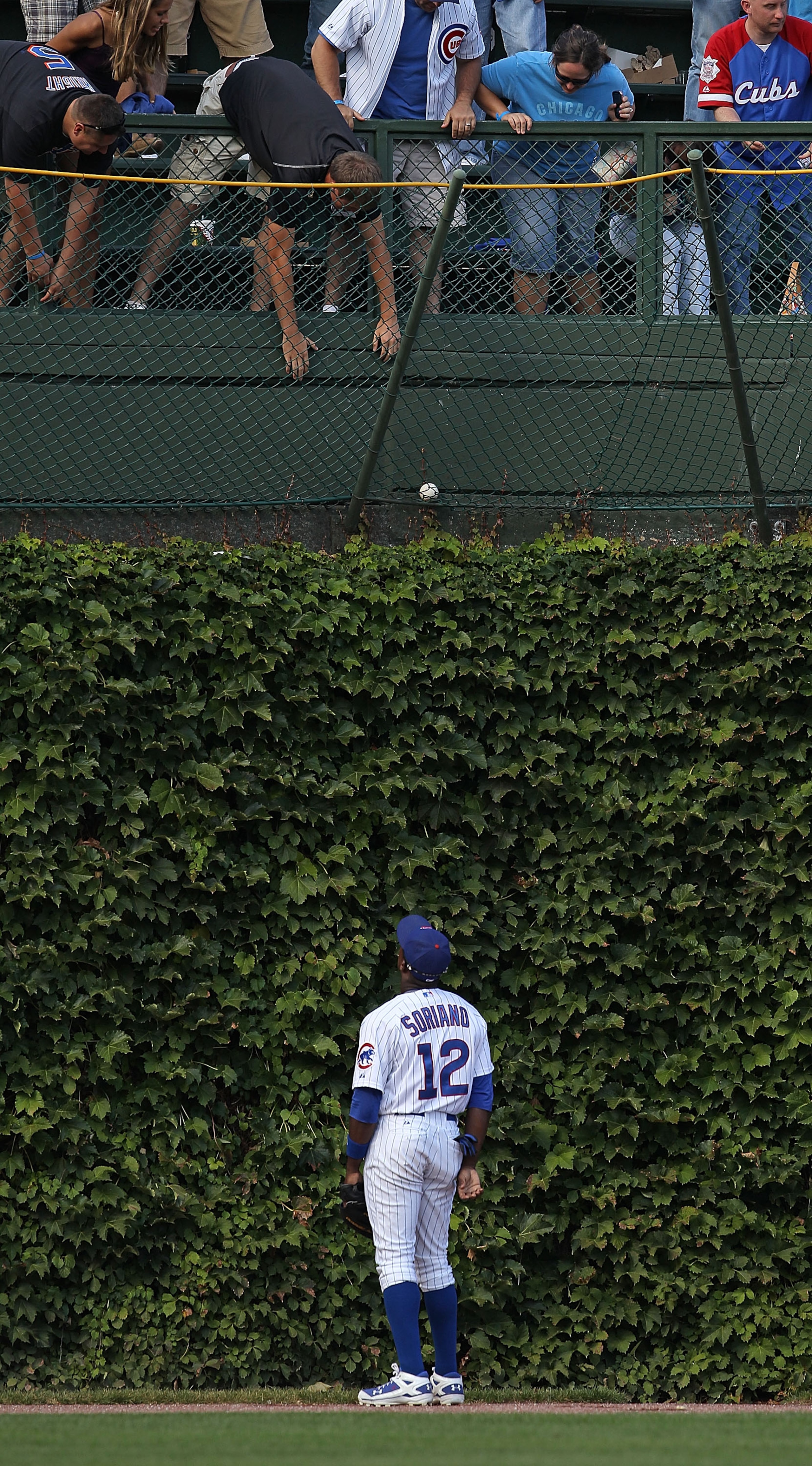CHICAGO - SEPTEMBER 05: Alfonso Soriano #12 of the Chicago Cubs watches as fans try to grab a home run ball hit by Ike Davis of the New York Mets out of the basket in left field at Wrigley Field on September 5, 2010 in Chicago, Illinois. (Photo by Jonatha
