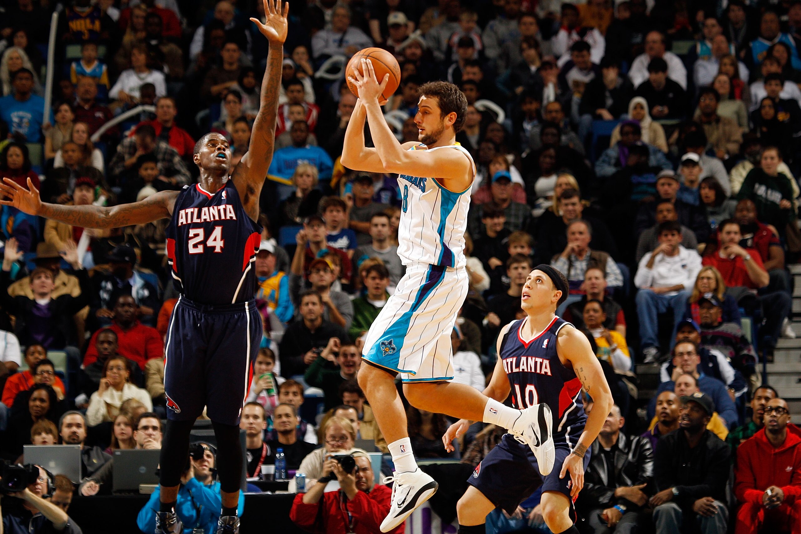 NEW ORLEANS, LA - DECEMBER 26:  Marco Belinelli #8 of the New Orleans Hornets passes the ball around Marvin Williams #24 of the Atlanta Hawks at the New Orleans Arena on December 26, 2010 in New Orleans, Louisiana.  The Hornets defeated the Hawks 93-86.