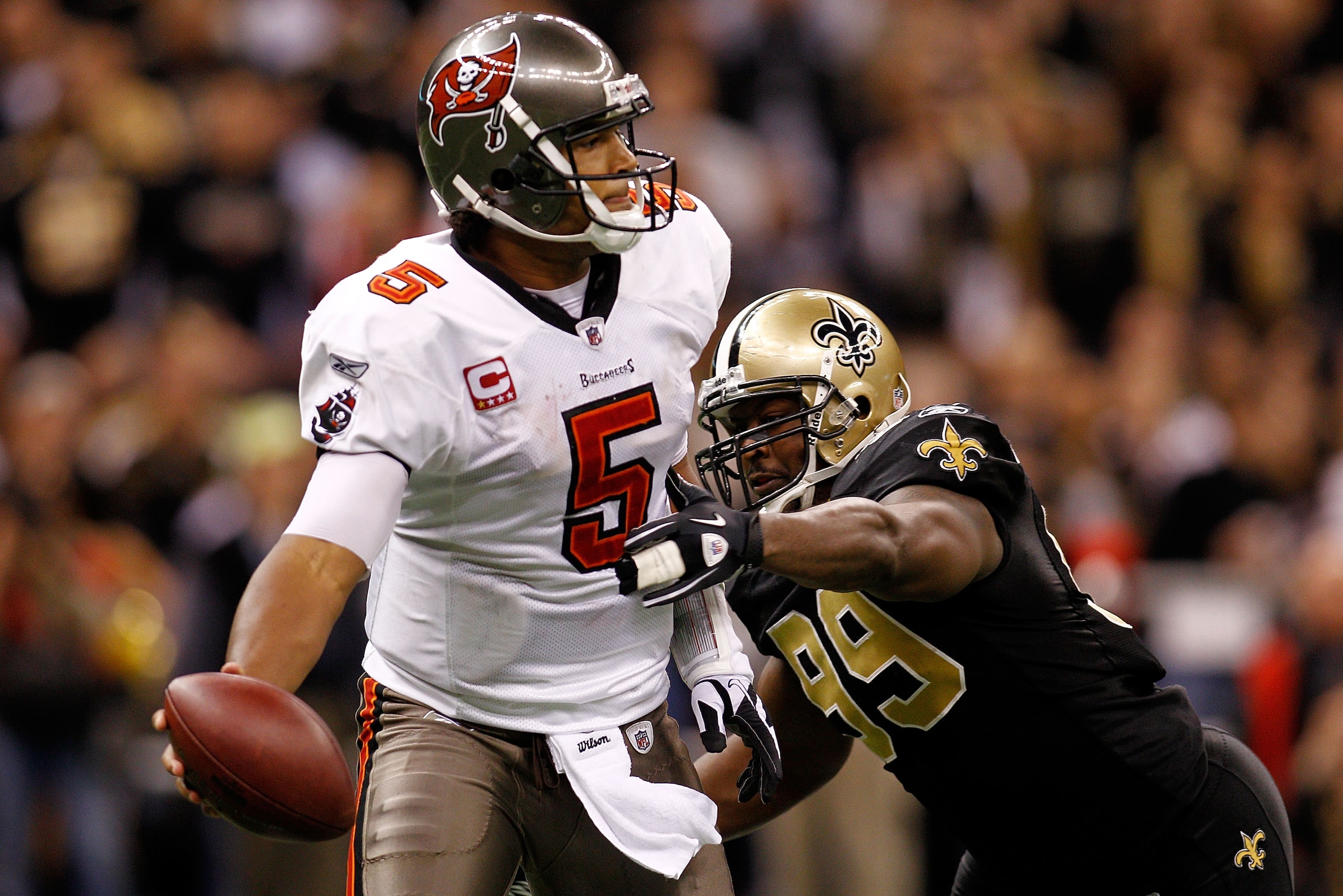 NEW ORLEANS, LA - JANUARY 02:  Quarterback Josh Freeman #5 of the Tampa Bay Buccaneers avoids a tackle by Jimmy Wilkerson #99 of the New Orleans Saints at the Louisiana Superdome on January 2, 2011 in New Orleans, Louisiana.   The Buccaneers defeated the 