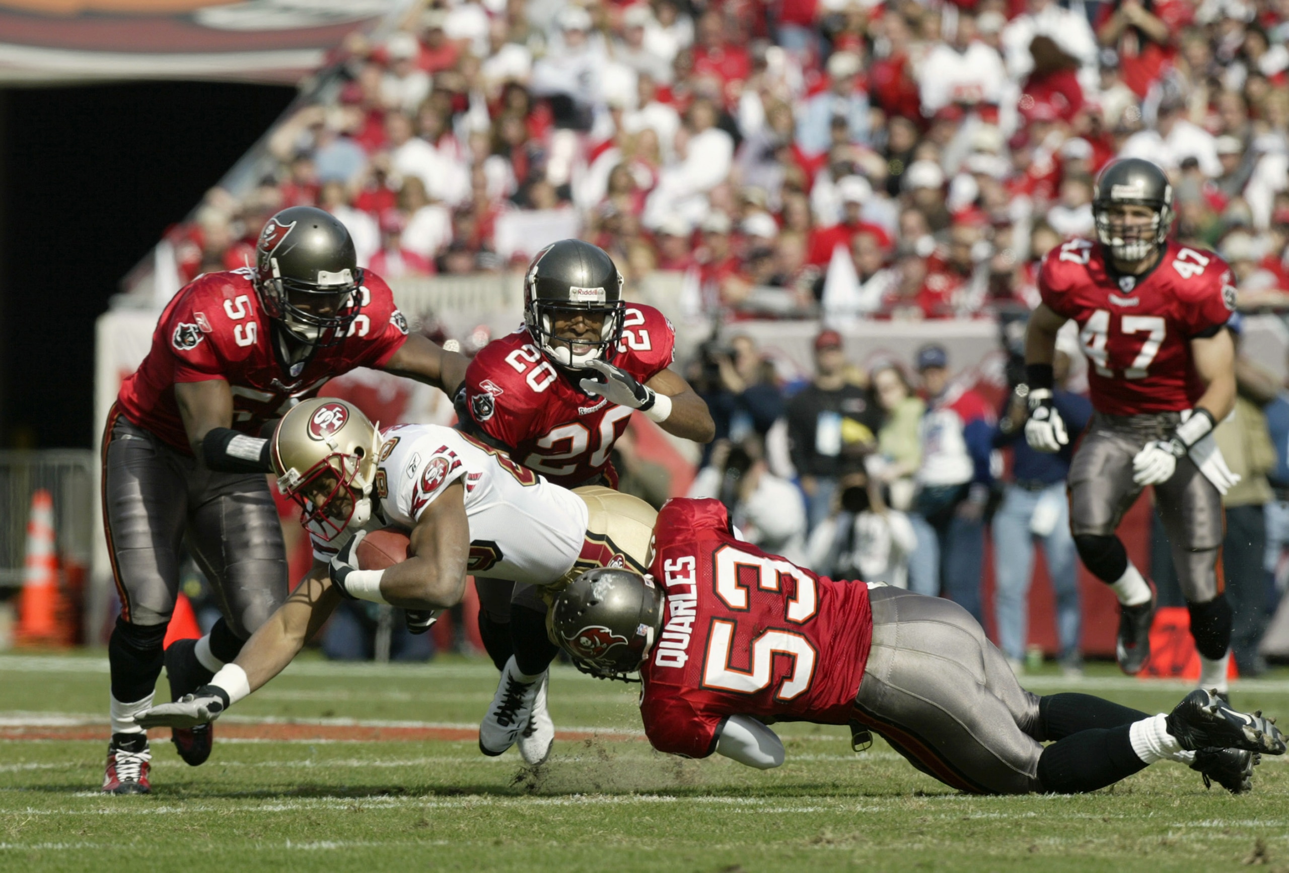 TAMPA, FL - JANUARY 12:  Wide receiver JJ Stokes #83 of the San Francisco 49ers is tackled by Derrick Brooks #55, Ronde Barber #20 and Shelton Quarles #53 of the Tampa Bay Buccaneers in the NFC Divisional Playoff game at Raymond James Stadium on January 1