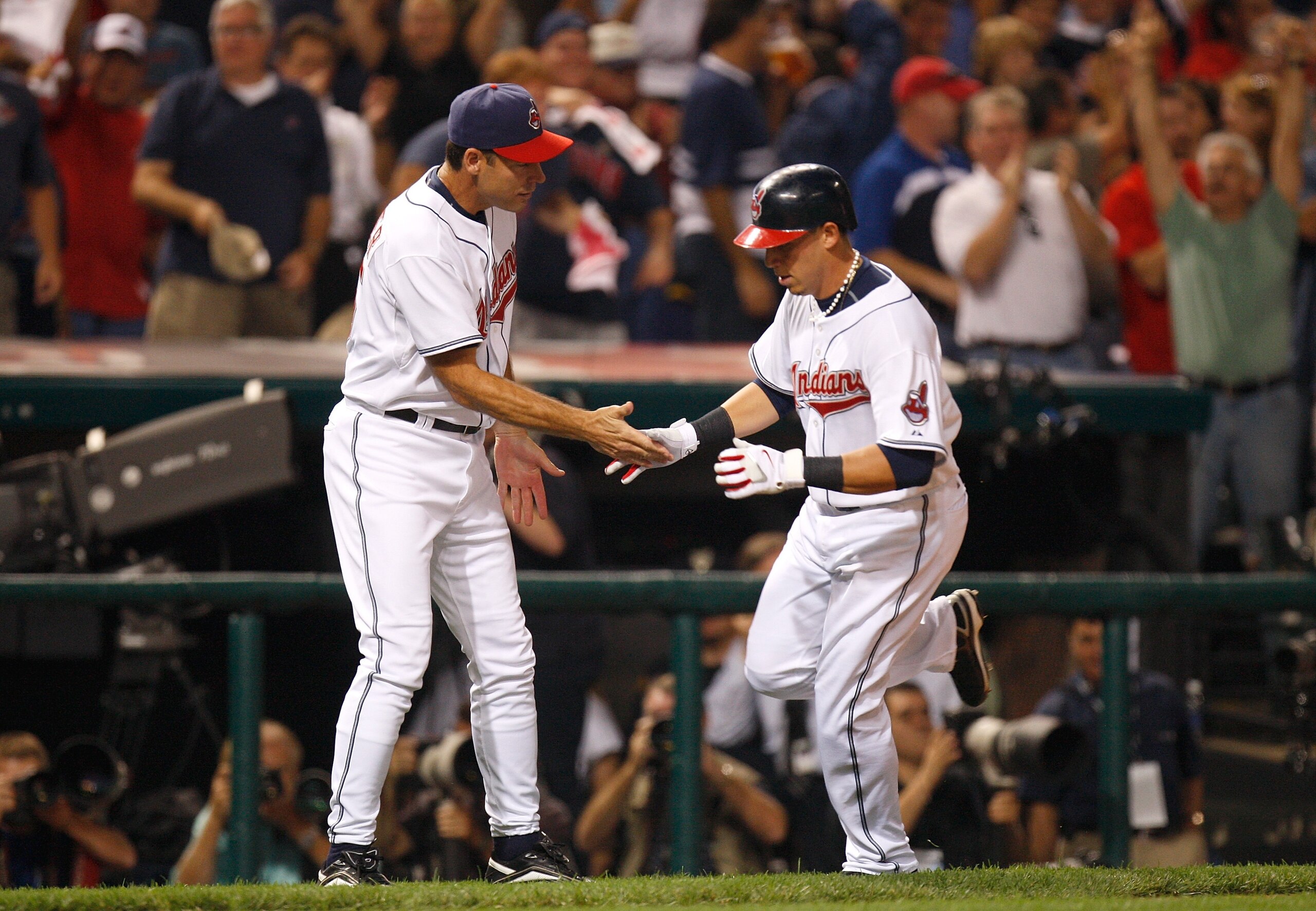 CLEVELAND - OCTOBER 04:  Asdrubal Cabera #13 of the Cleveland Indians is congratulated thirdbase coach Joel Skinner (R) as he heads to home plate after hitting a solo home run in the bottom of the third inning against the New York Yankees during Game One