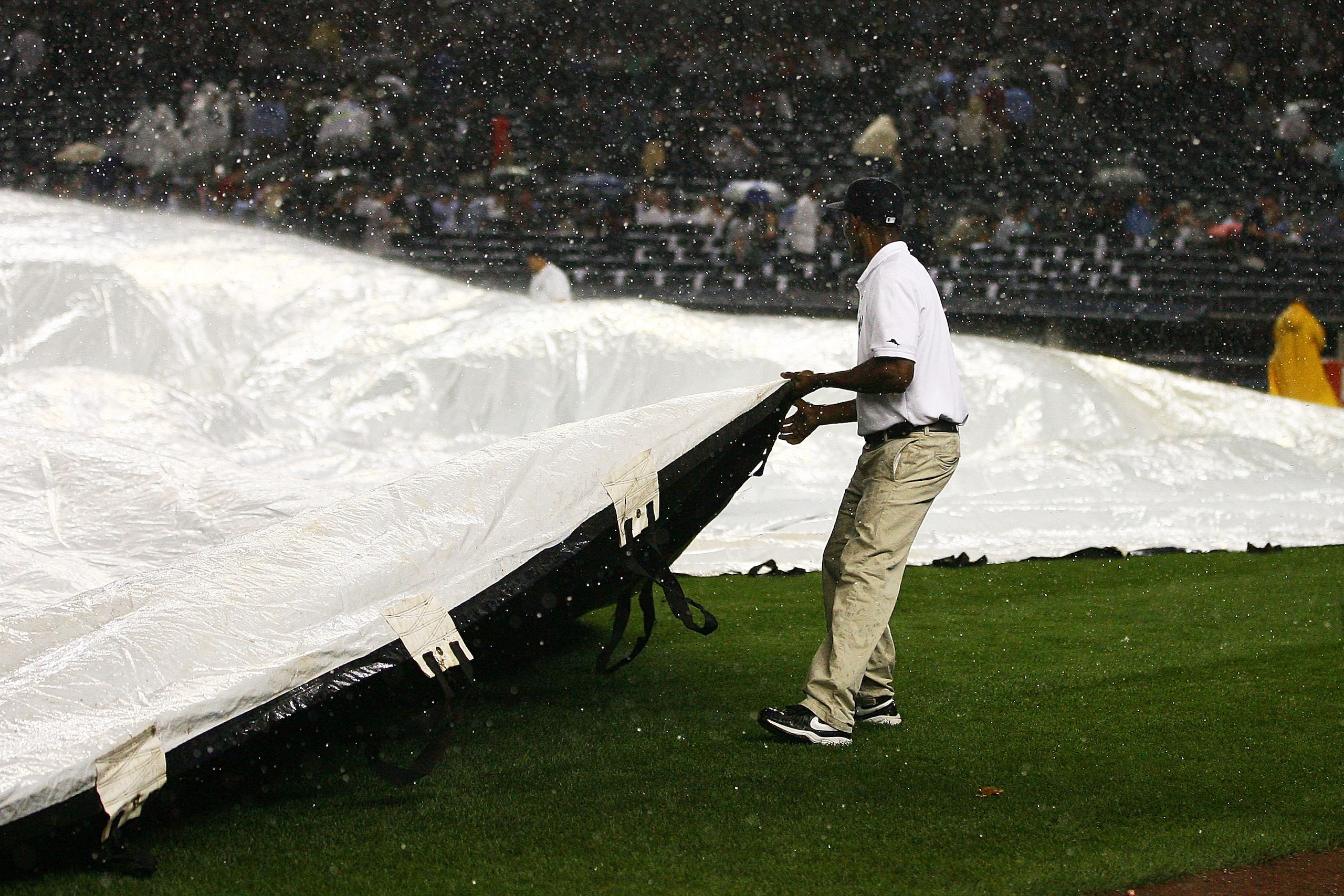 NEW YORK - SEPTEMBER 22:  Members of the New York Yankees grounds keeping crew cover the field at the start of a rain delay during the third inning against the Tampa Bay Rays on September 22, 2010 at Yankee Stadium in the Bronx borough of New York City.