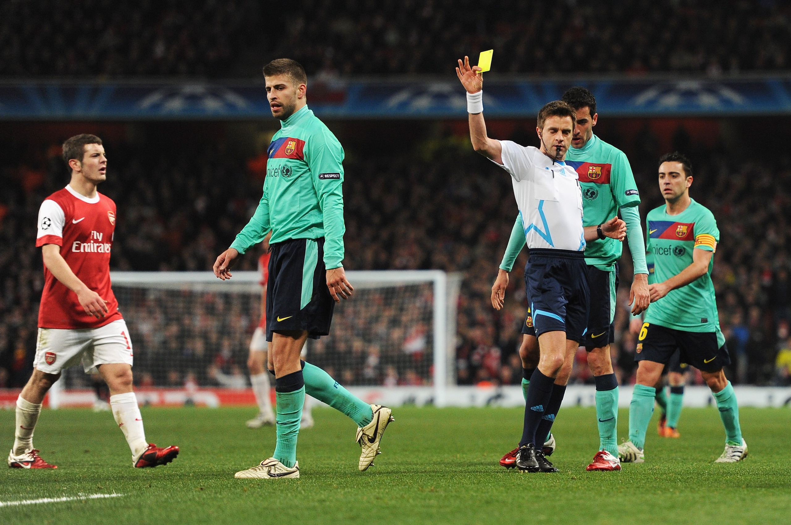LONDON, ENGLAND - FEBRUARY 16: Referee Nicola Rizzoli shows the yellow card to Gerard Pique of Barcelona during the UEFA Champions League round of 16 first leg match between Arsenal and Barcelona at the Emirates Stadium on February 16, 2011 in London, Eng