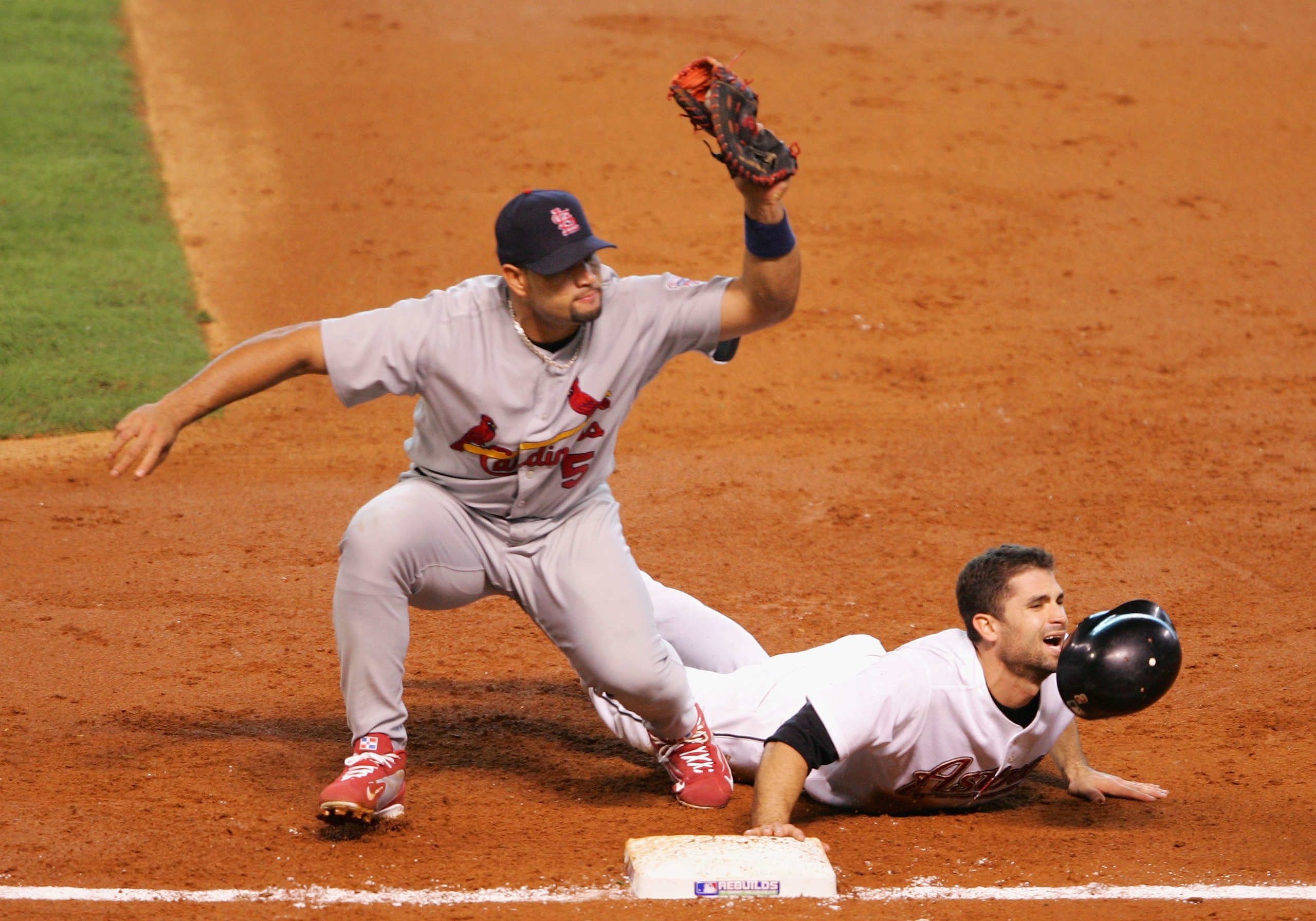 HOUSTON - OCTOBER 15:  Chris Burke #2 of the Houston Astros slides safely back into first base under the tag from Albert Pujols #5 of the St. Louis Cardinals during Game Three of the National League Championship Series at Minute Maid Park on October 15, 2