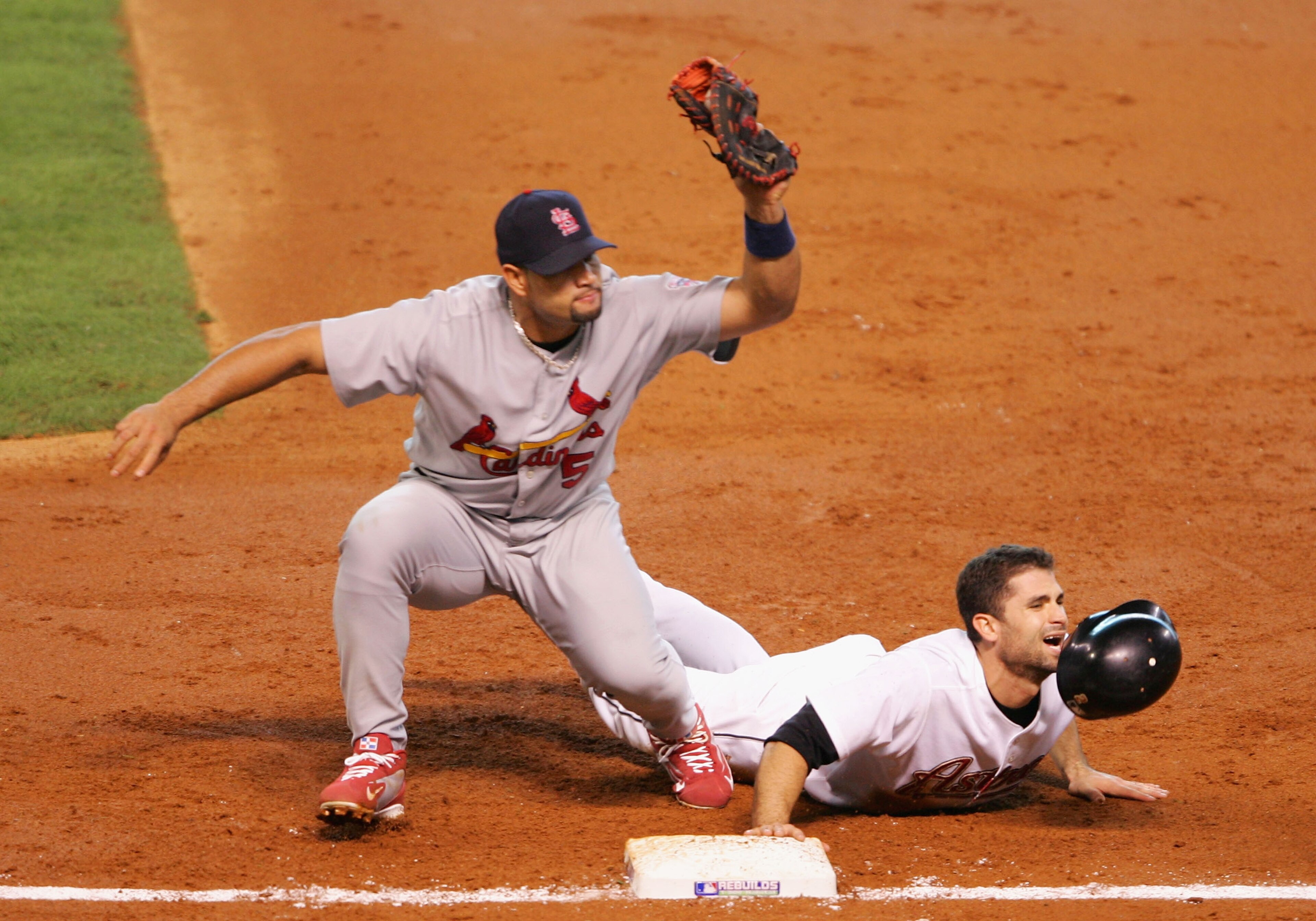 HOUSTON - OCTOBER 15:  Chris Burke #2 of the Houston Astros slides safely back into first base under the tag from Albert Pujols #5 of the St. Louis Cardinals during Game Three of the National League Championship Series at Minute Maid Park on October 15, 2