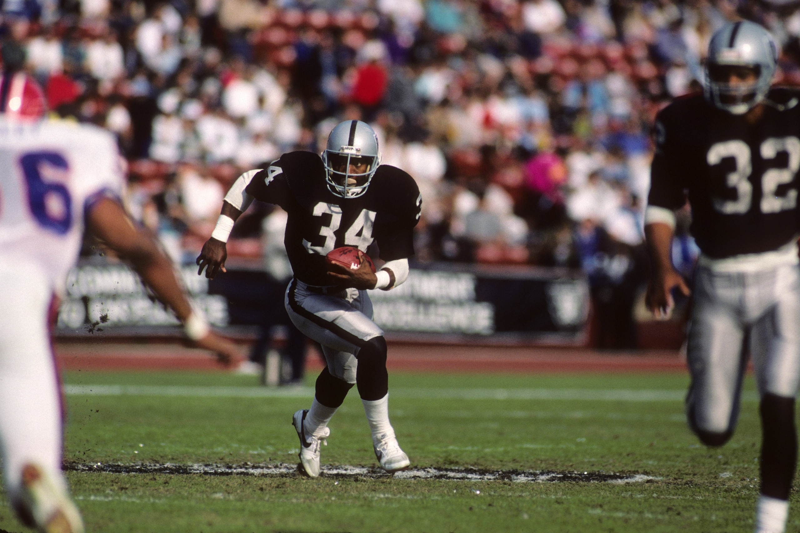LOS ANGELES - DECEMBER 6:  Running back Bo Jackson #34 of Los Angeles Raiders follows the lead of teammate Marcus Allen #32 agains the Buffalo Bills defense during the game at the Los Angeles Memorial Coliseum on December 6, 1987 in Los Angeles, Californi