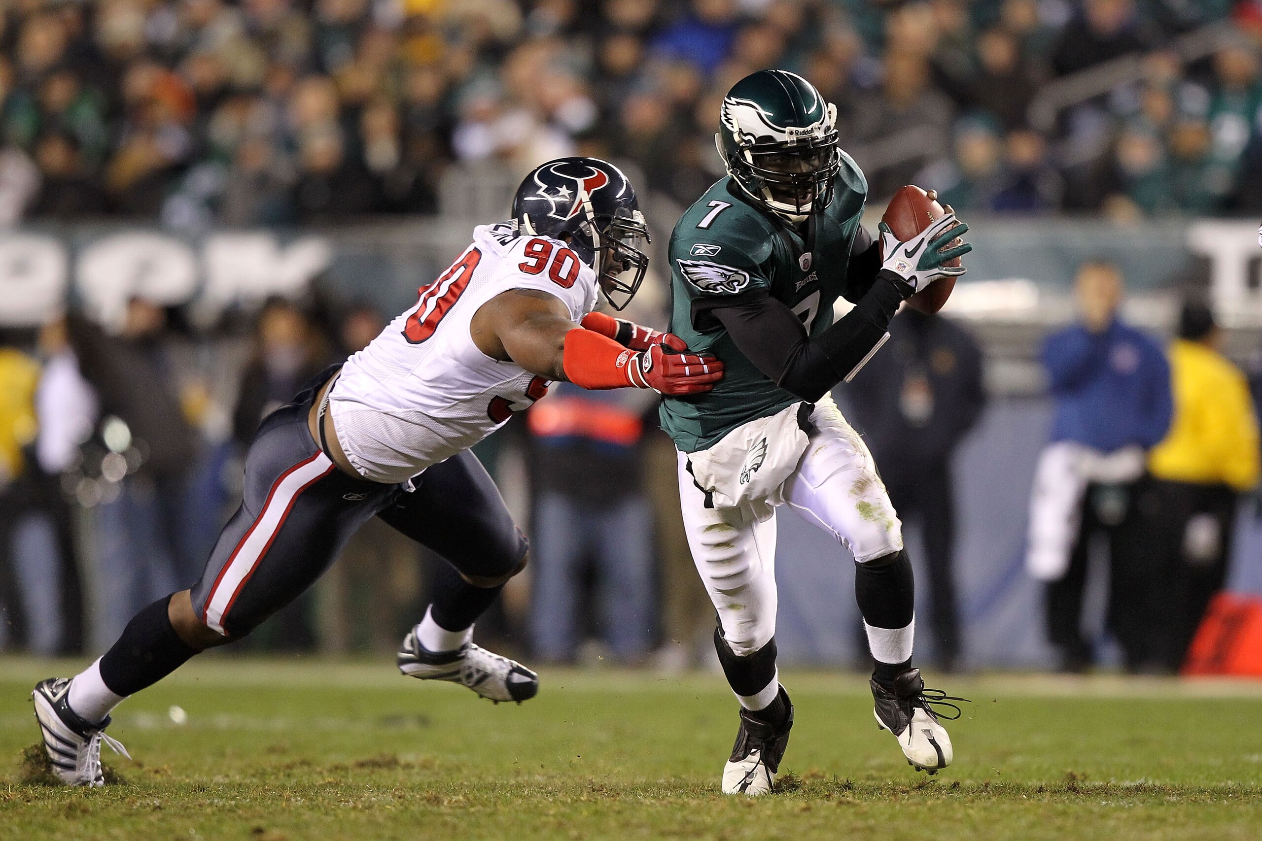 PHILADELPHIA, PA - DECEMBER 02:  Michael Vick #7 of the Philadelphia Eagles runs with the ball as he elludes the pass rush from Mario Williams #90 of the Houston Texans at Lincoln Financial Field on December 2, 2010 in Philadelphia, Pennsylvania.  (Photo