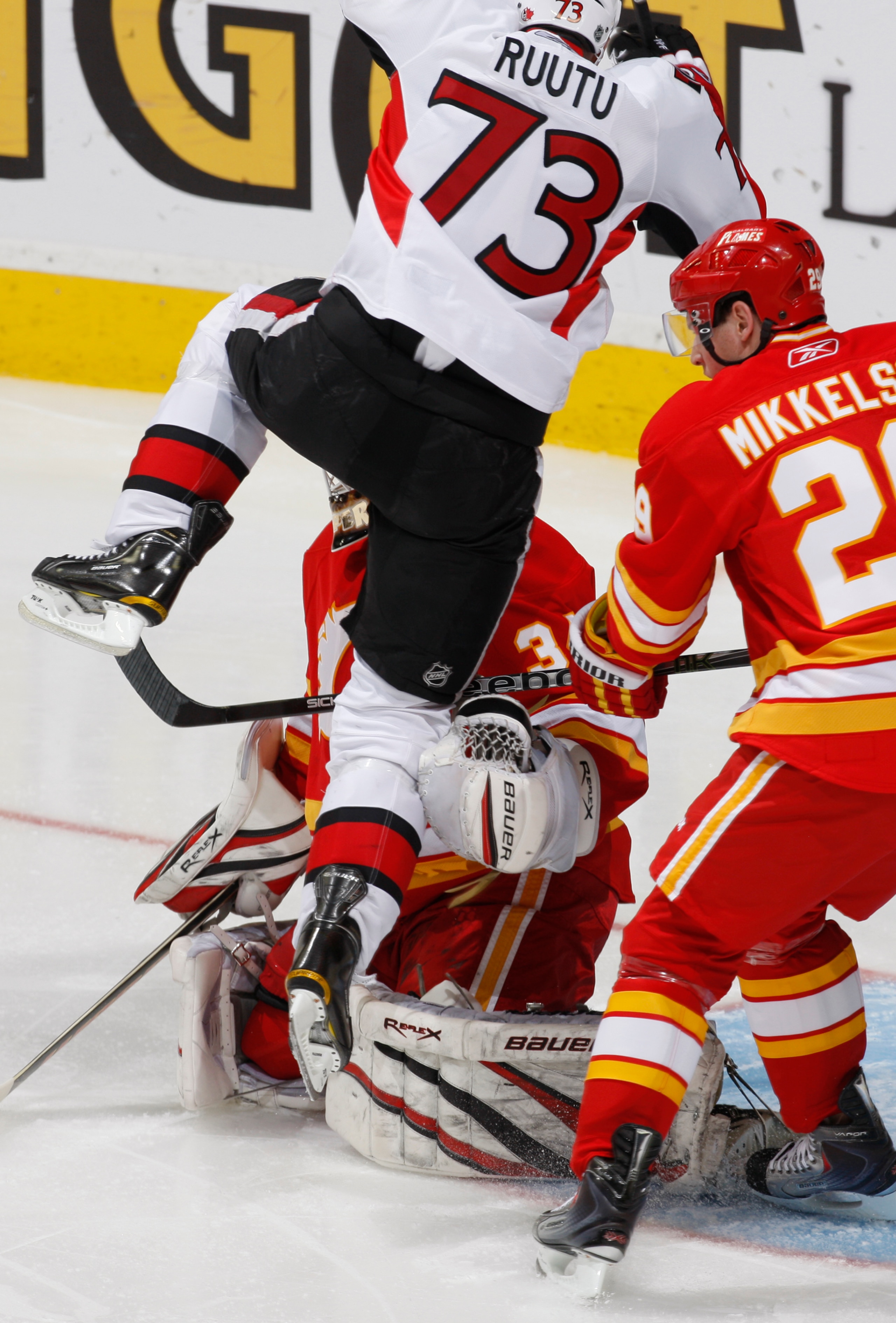 CALGARY, CANADA - FEBRUARY 9:  Miikka Kirusoff #34 of the Calgary Flames is run into by Jarkko Ruutu #73 of the Ottawa Senators in first period action at Scotiabank Saddledome February 9, 2011 in Calgary, Alberta, Canada. (Photo by Dale MacMillan/Getty Im
