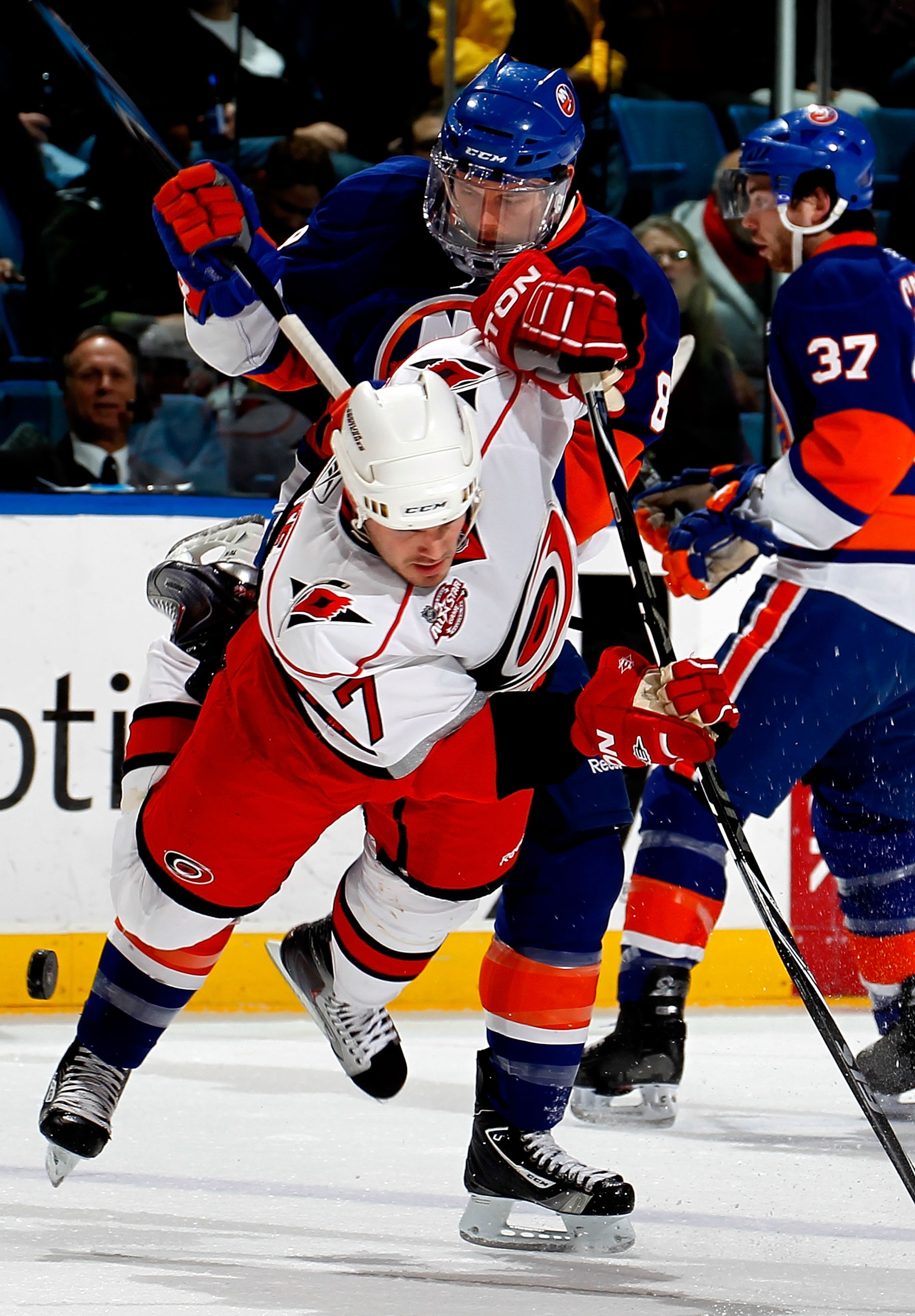 UNIONDALE, NY - JANUARY 26:  Ian White #7 of the Carolina Hurricanes is knocked off the puck by Bruno Gervais #8 of the New York Islanders during the second period of an NHL hockey game at the Nassau Coliseum on January 26, 2011 in Uniondale, New York.  (