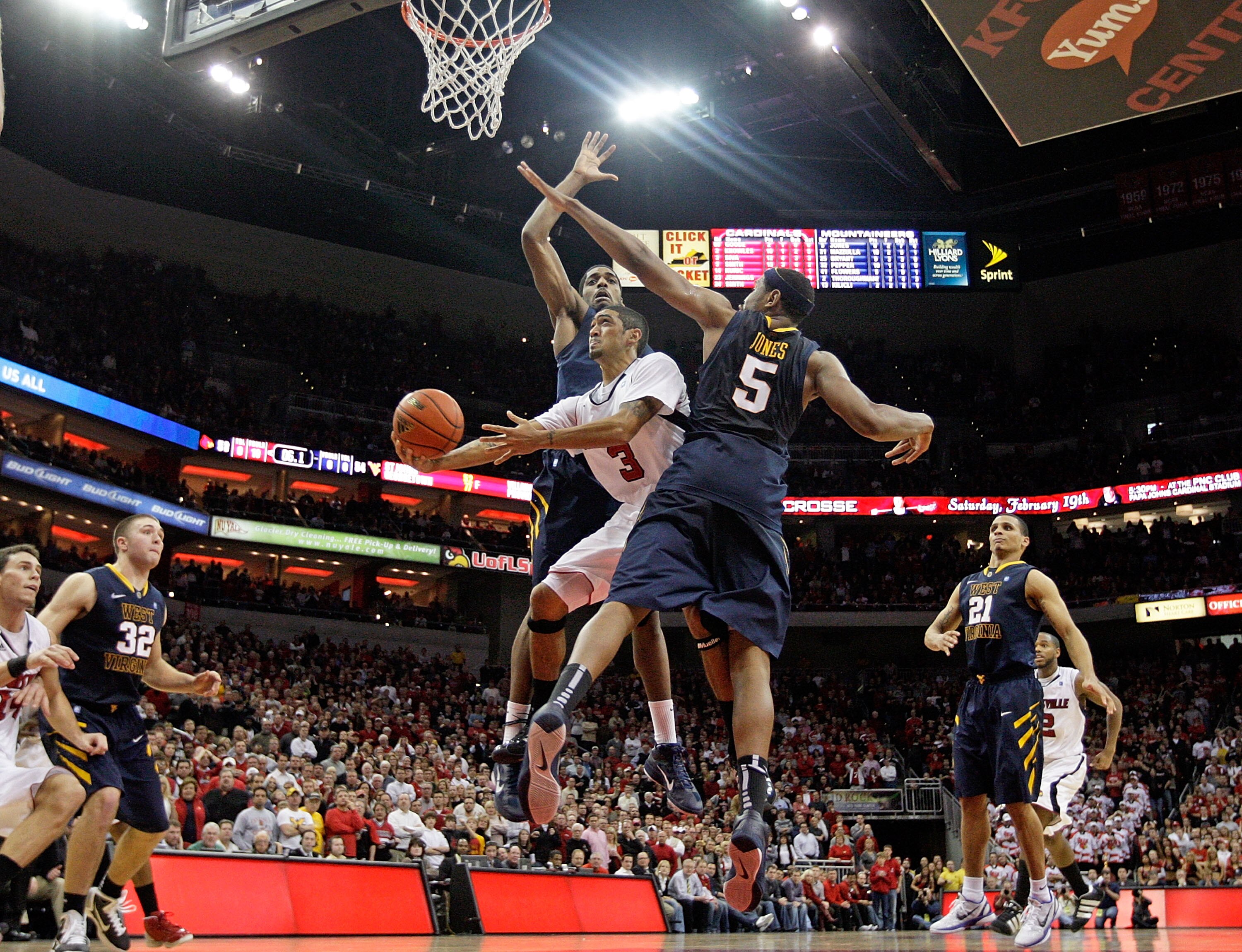 LOUISVILLE, KY - JANUARY 26:  Peyton Siva #3 of the Louisville Cardinals shoots the game winning shot while defended by John Flowers #41 and Kevin Jones #5 of  the West Virginia Mountaineers during the big East Conference at the KFC Yum! Center on January