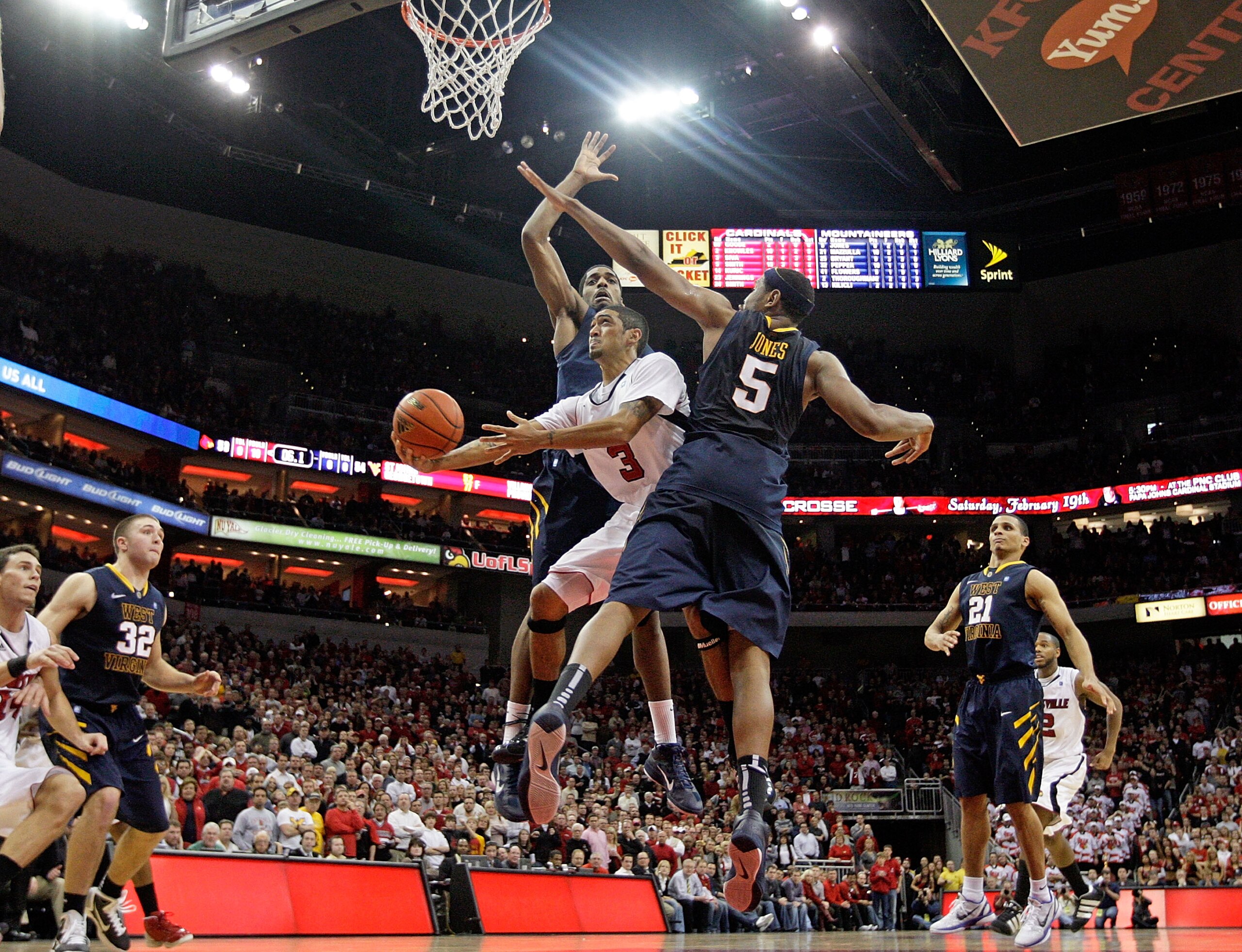 LOUISVILLE, KY - JANUARY 26:  Peyton Siva #3 of the Louisville Cardinals shoots the game winning shot while defended by John Flowers #41 and Kevin Jones #5 of  the West Virginia Mountaineers during the big East Conference at the KFC Yum! Center on January