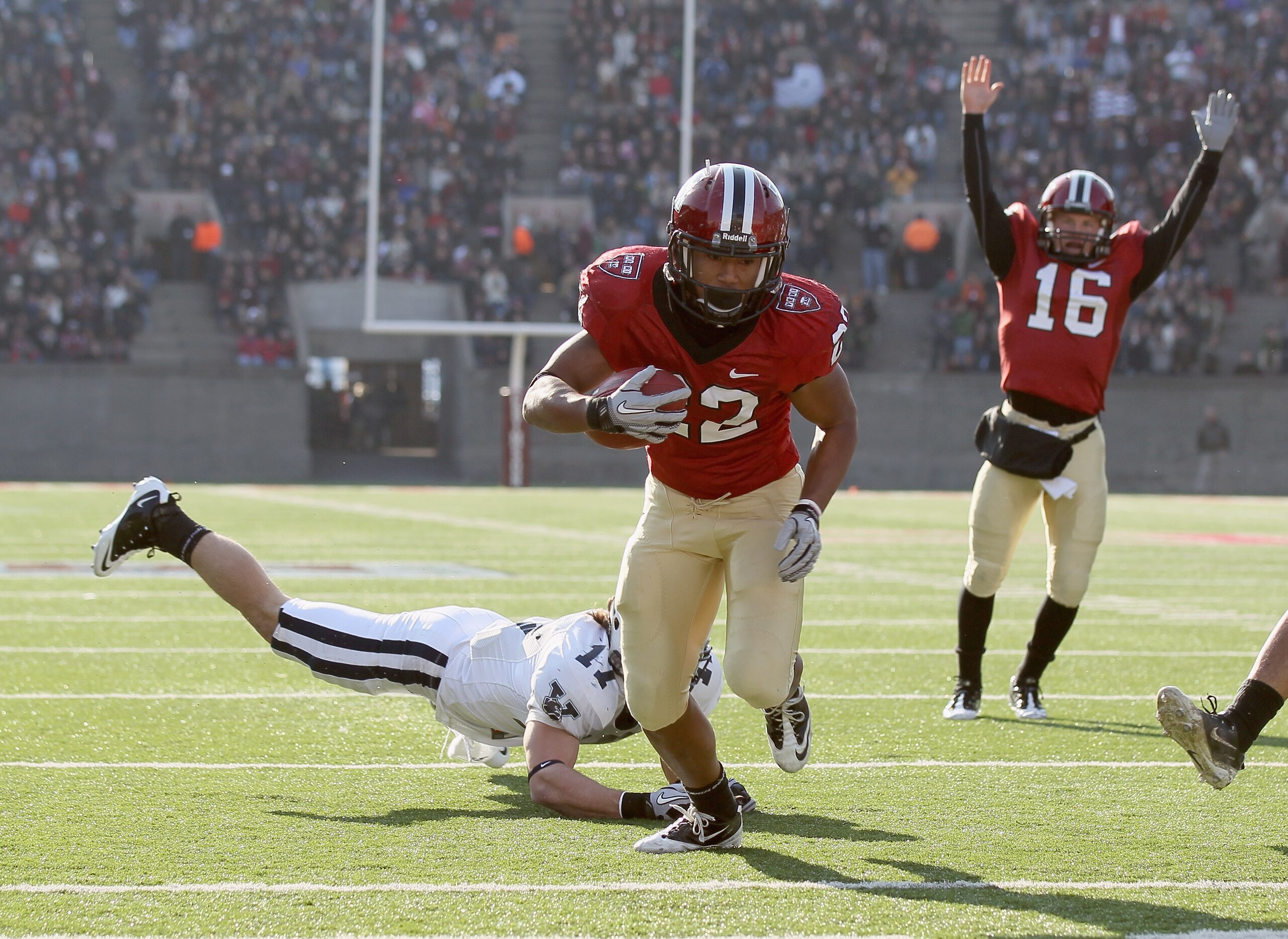 CAMBRIDGE, MA - NOVEMBER 20: Gino Gordon #22 of the Harvard Crimson gets by Adam Money #17 of the Yale Bulldogs to score a touchdown as Colliers Winter #16 of Harvard celebrates on November 20, 2010 at Harvard Stadium in Cambridge, Massachusetts. Harvar CAMBRIDGE, MA - NOVEMBER 20: Gino Gordon #22 of the Harvard Crimson gets by Adam Money #17 of the Yale Bulldogs to score a touchdown as Colliers Winter #16 of Harvard celebrates on November 20, 2010 at Harvard Stadium in Cambridge, Massachusetts. Harvar
