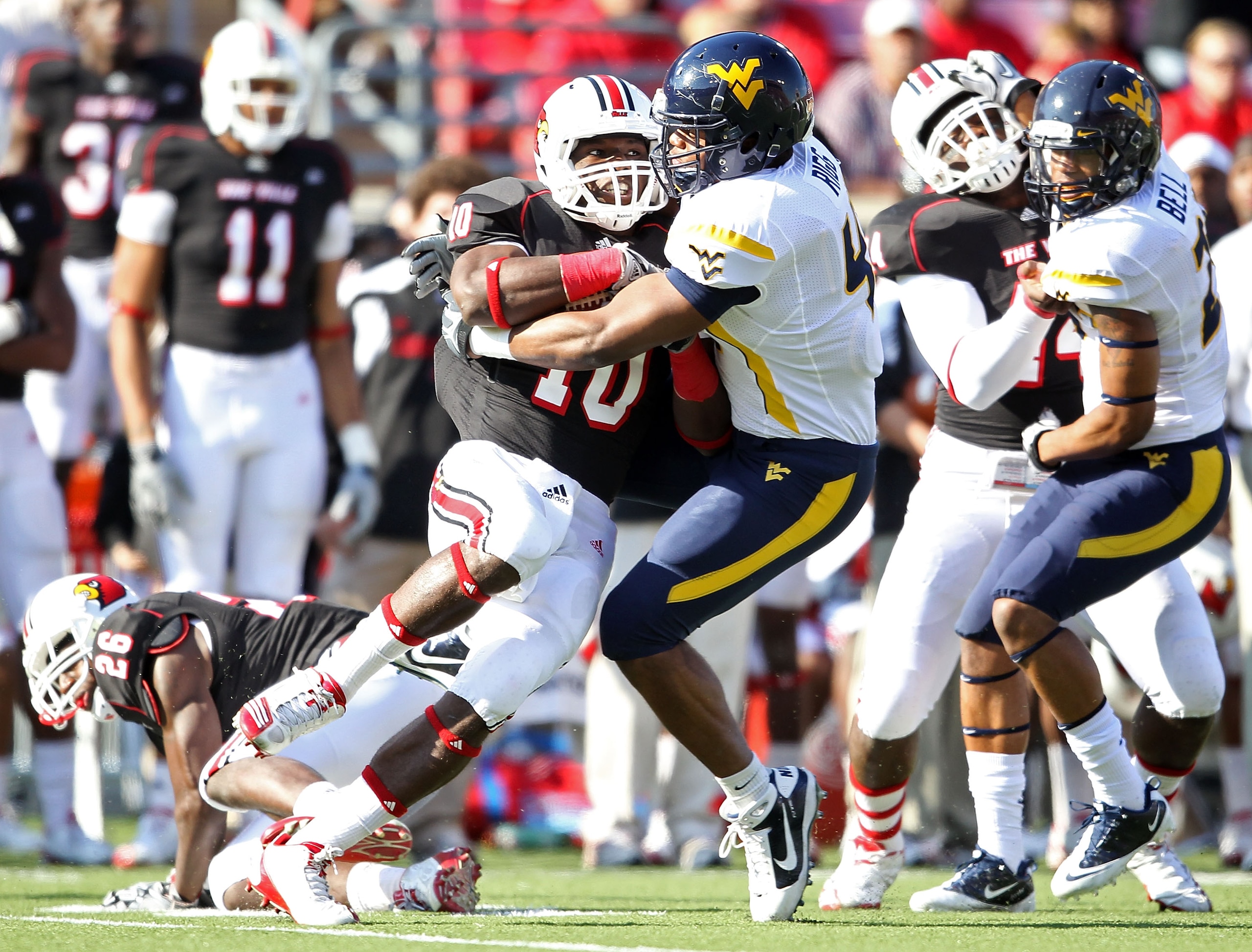 LOUISVILLE, KY - NOVEMBER 20:  Dominique Brown #10 of the Louisville Cardinals is tackled by Doug Rigg #47 of the West Virginia Mountaineers during the game at Papa John's Cardinal Stadium on November 20, 2010 in Louisville, Kentucky.  (Photo by Andy Lyon