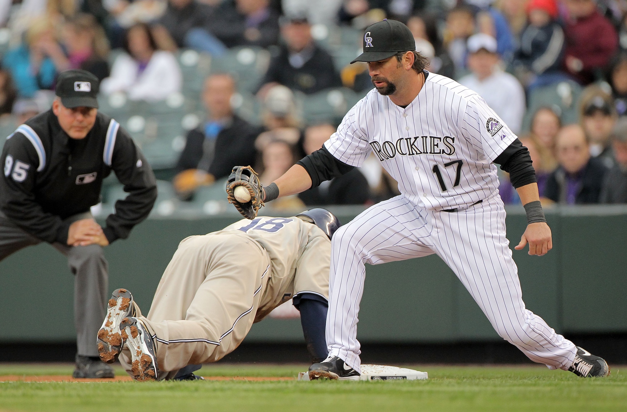 DENVER - APRIL 10:  First baseman Todd Helton #17 of the Colorado Rockies takes a pick off throw at first base to hold Tony Gwynn Jr. #18 of the San Diego Padres as umpire Tim Timmons oversees the play during MLB action at Coors Field on April 10, 2010 in