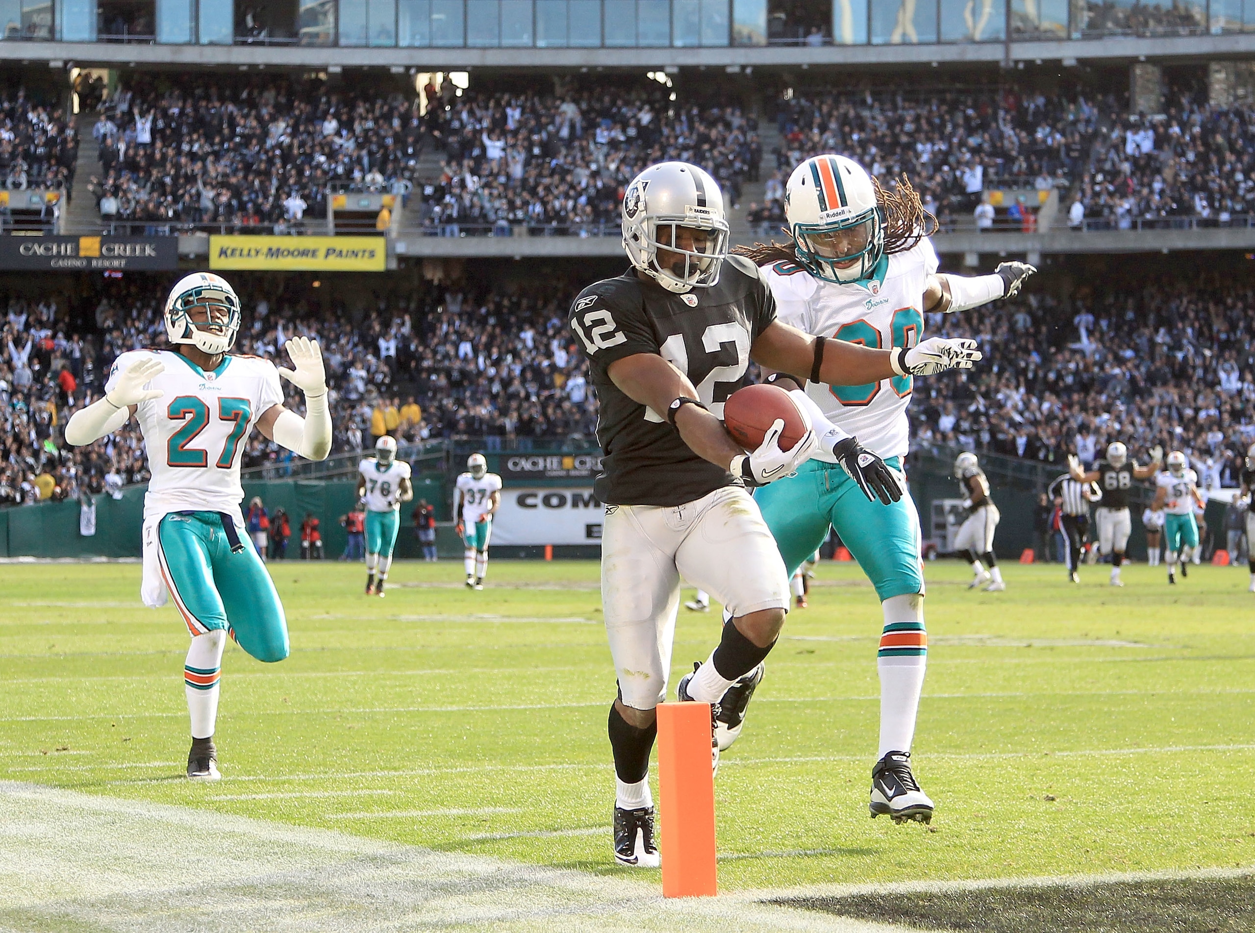 OAKLAND, CA - NOVEMBER 28:  Jacoby Ford #12 of the Oakland Raiders runs past Benny Sapp #27 and Chris Clemons #30 of the Miami Dolphins to score a touchdown at Oakland-Alameda County Coliseum on November 28, 2010 in Oakland, California.  (Photo by Ezra Sh