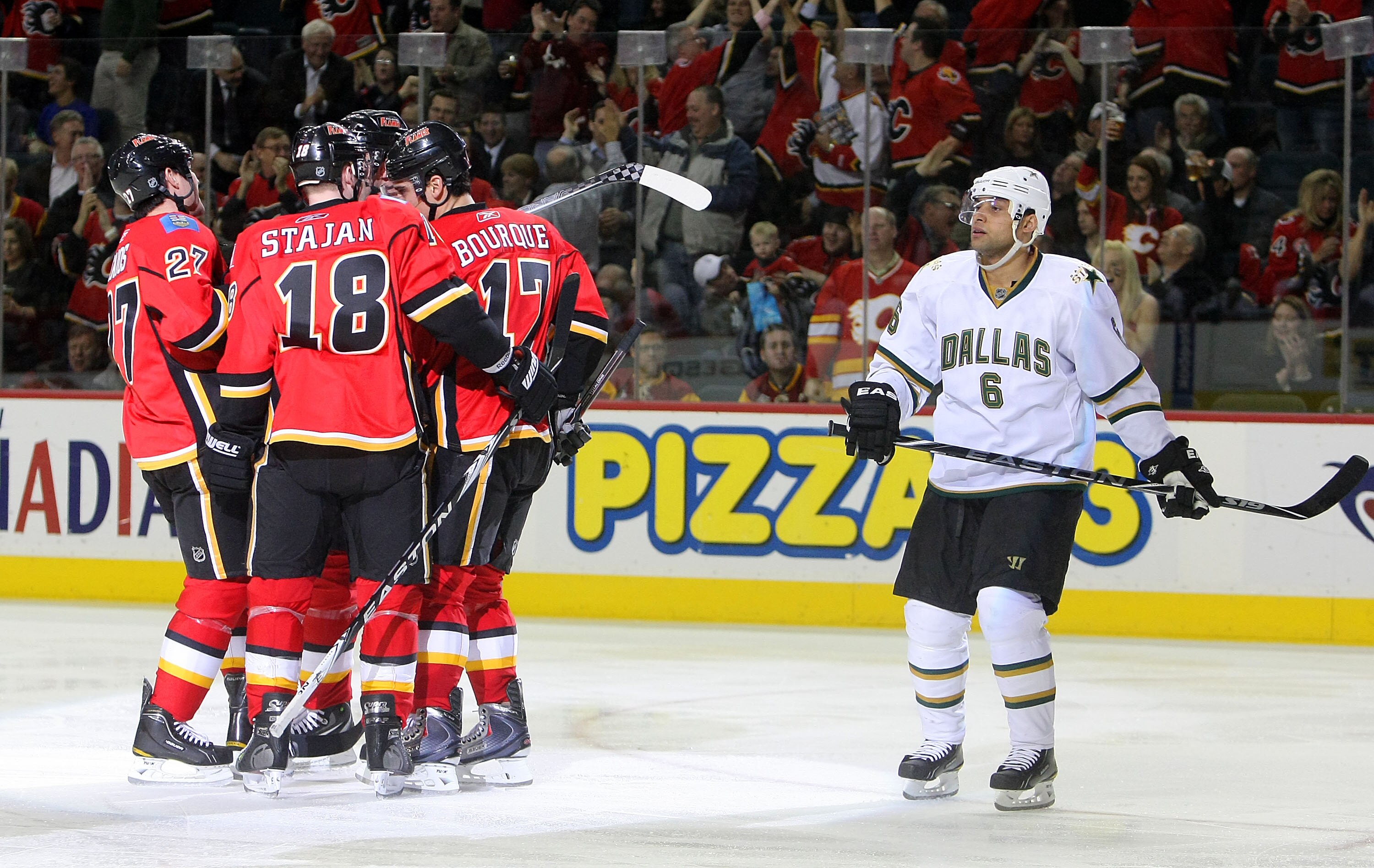 CALGARY, CANADA - FEBRUARY 16:  Steve Staios #27 of the Calgary Flames (not pictured) celebrates his goal scored against the Dallas Stars with teammates Matt Stajan #18 and Rene Bourque #17 as Trevor Daley #6 of the Dallas Stars skates back to the bench d