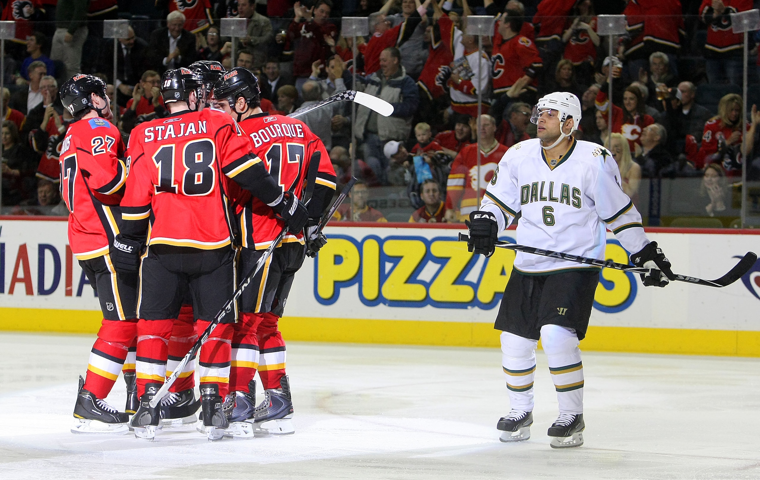 CALGARY, CANADA - FEBRUARY 16:  Steve Staios #27 of the Calgary Flames (not pictured) celebrates his goal scored against the Dallas Stars with teammates Matt Stajan #18 and Rene Bourque #17 as Trevor Daley #6 of the Dallas Stars skates back to the bench d