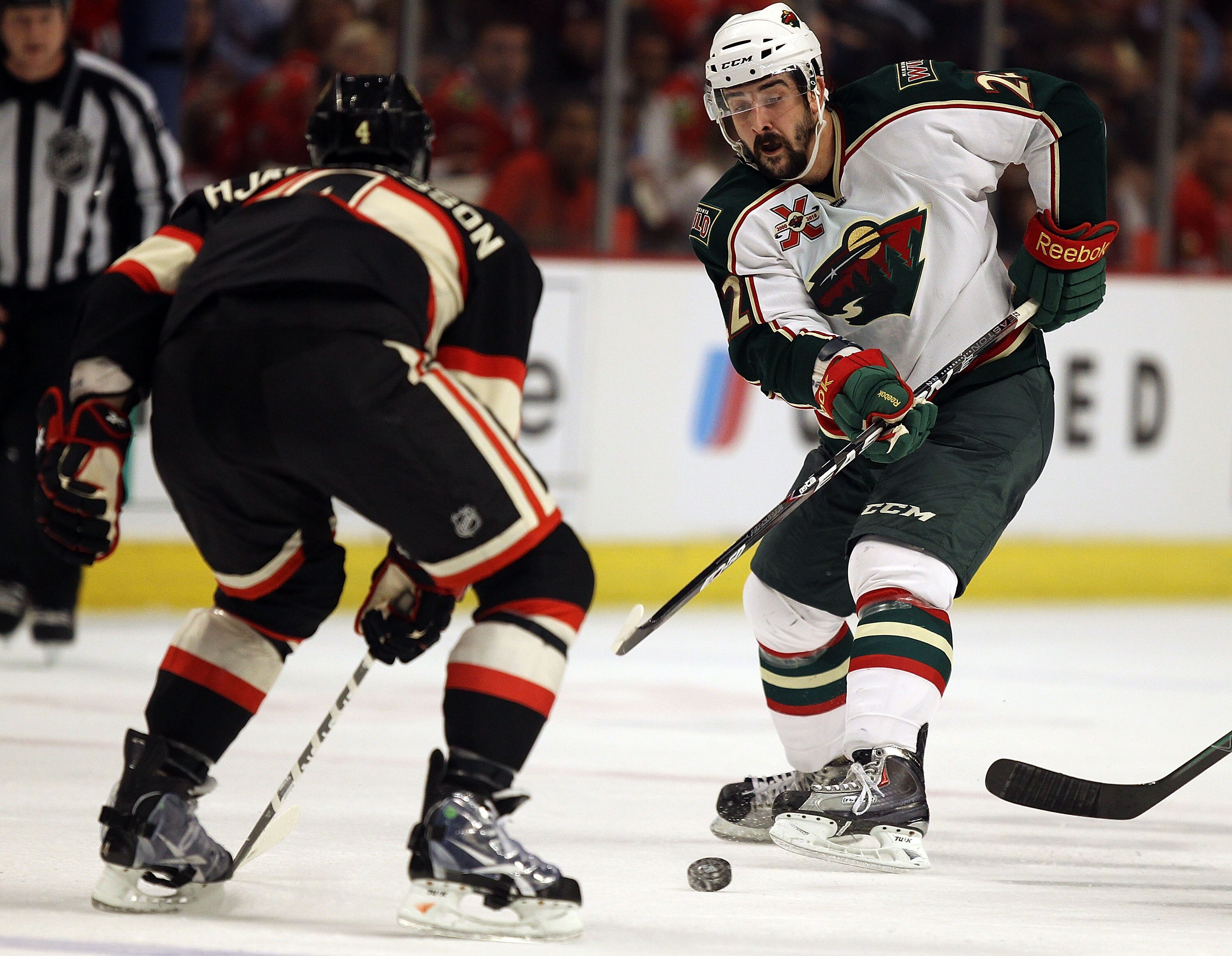 CHICAGO, IL - JANUARY 25: Cal Clutterbuck #22 of the Minnesota Wild passes the puck around Niklas Hjalmarsson #4 of the Chicago Blackhawks at the United Center on January 25, 2011 in Chicago, Illinois. (Photo by Jonathan Daniel/Getty Images)