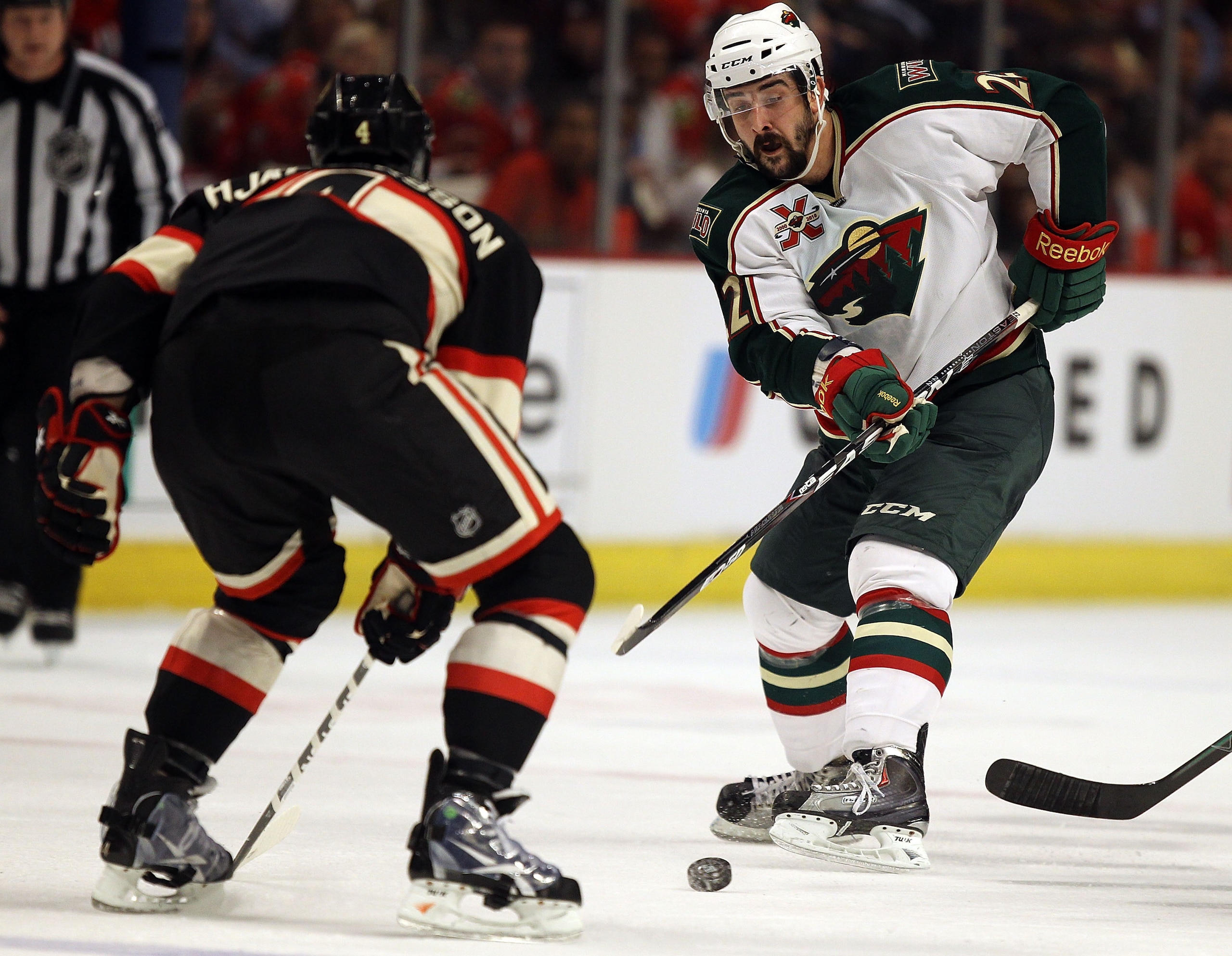CHICAGO, IL - JANUARY 25: Cal Clutterbuck #22 of the Minnesota Wild passes the puck around Niklas Hjalmarsson #4 of the Chicago Blackhawks at the United Center on January 25, 2011 in Chicago, Illinois. (Photo by Jonathan Daniel/Getty Images)