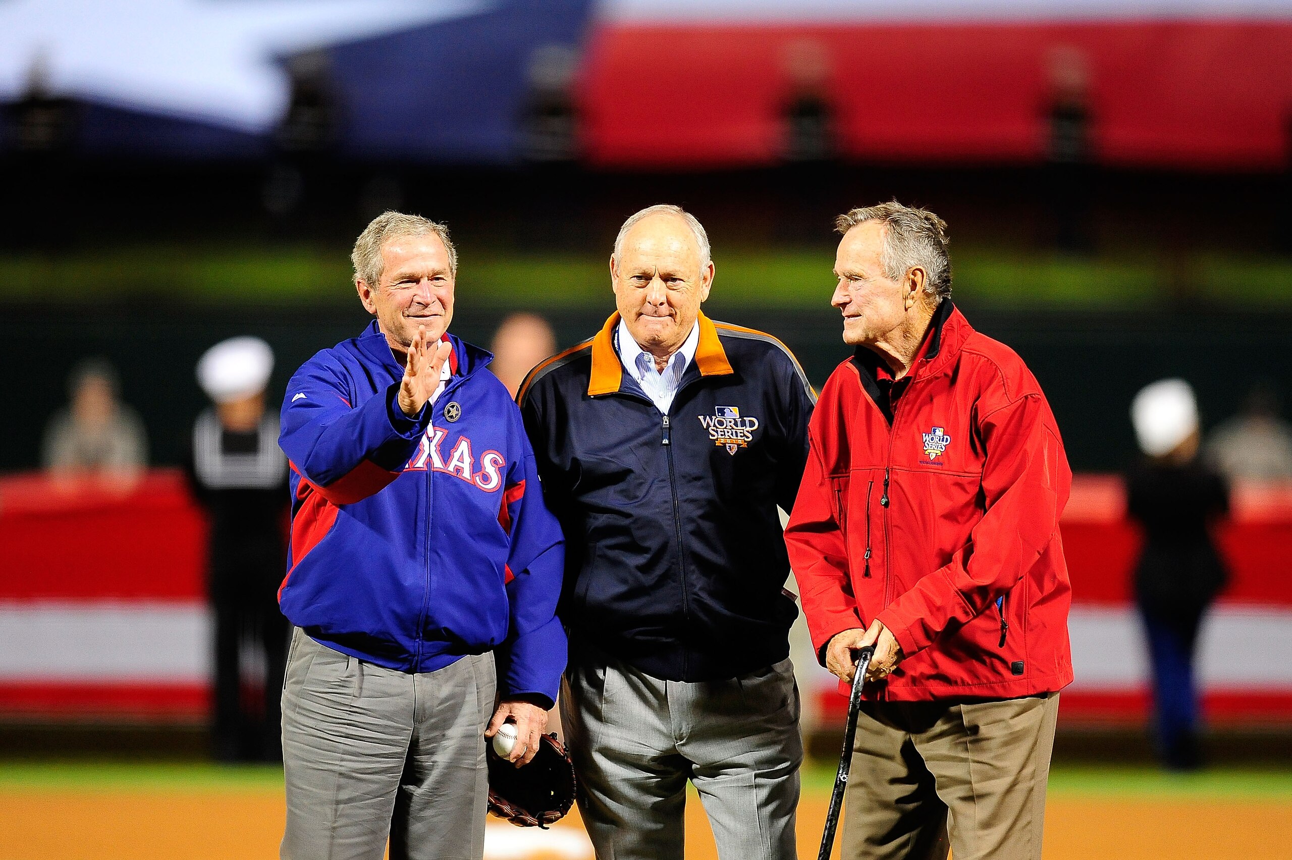 ARLINGTON, TX - OCTOBER 31:  Former President of the United States, George W. Bush (L), and his father Former President George H.W. Bush wave to the crowd with Rangers' President Nolan Ryan (C) before the Texas Rangers host the San Francisco Giants in Gam