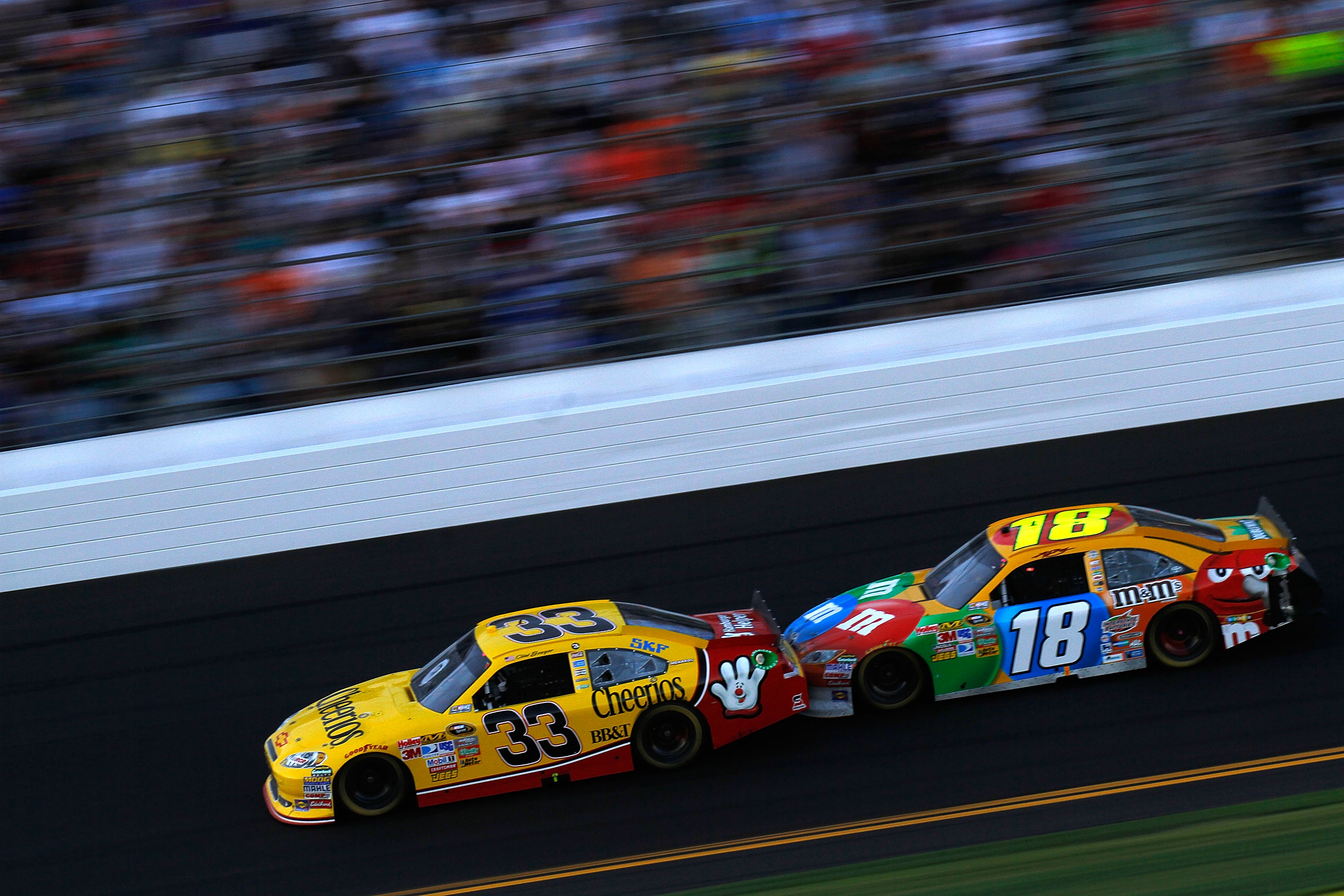 DAYTONA BEACH, FL - FEBRUARY 20:  Clint Bowyer, driver of the #33 Cheerios Chevrolet,  and Kyle Busch, driver of the #18 M&M'sToyota, race during the NASCAR Sprint Cup Series Daytona 500 at Daytona International Speedway on February 20, 2011 in Daytona Be