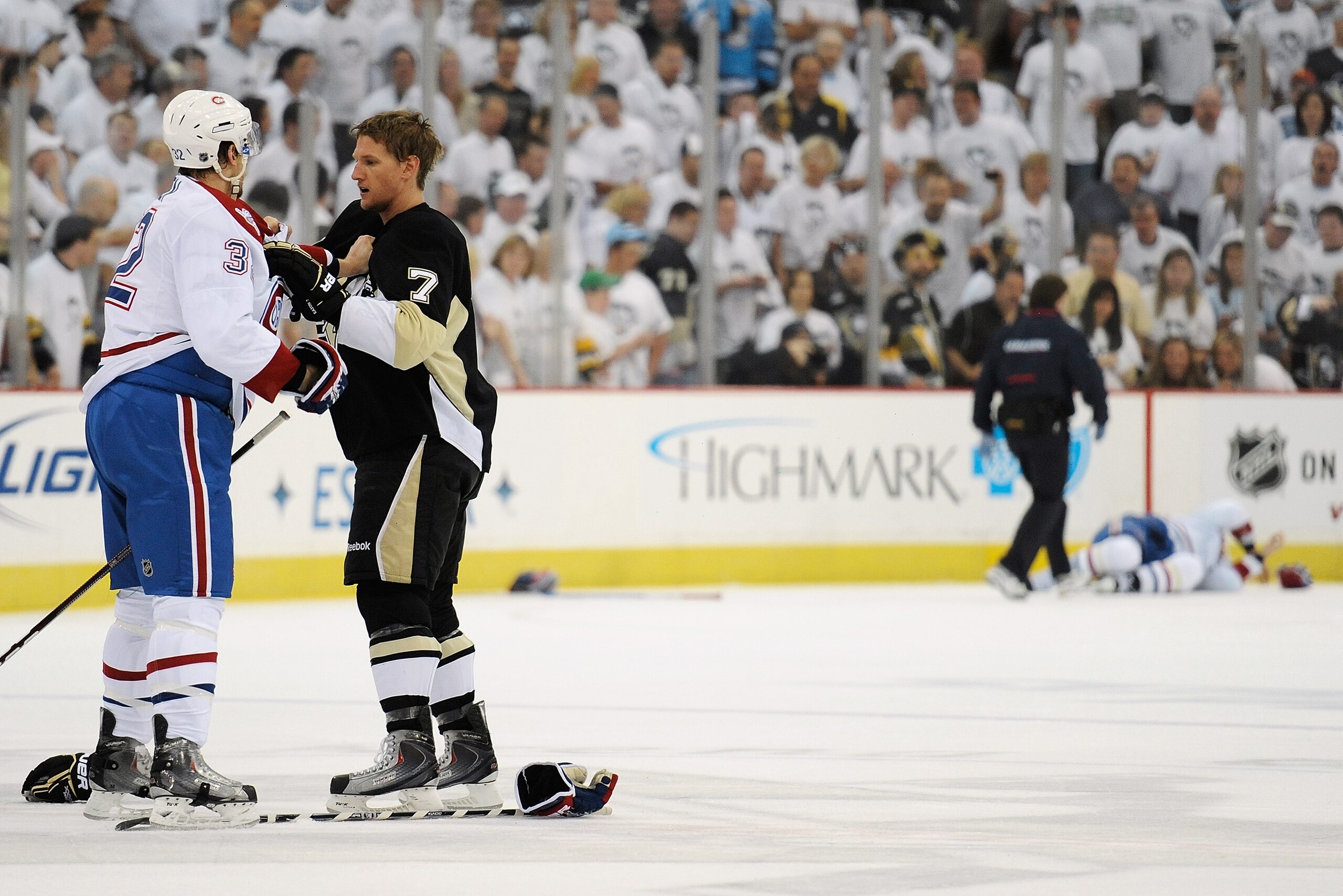 PITTSBURGH - APRIL 30:  Travis Moen #32 of the Montreal Canadiens squares off with Mark Eaton #7 of the Pittsburgh Penguins at center ice as Andrei Markov #79 of the Canadiens lies injured in the background in Game One of the Eastern Conference Semifinals