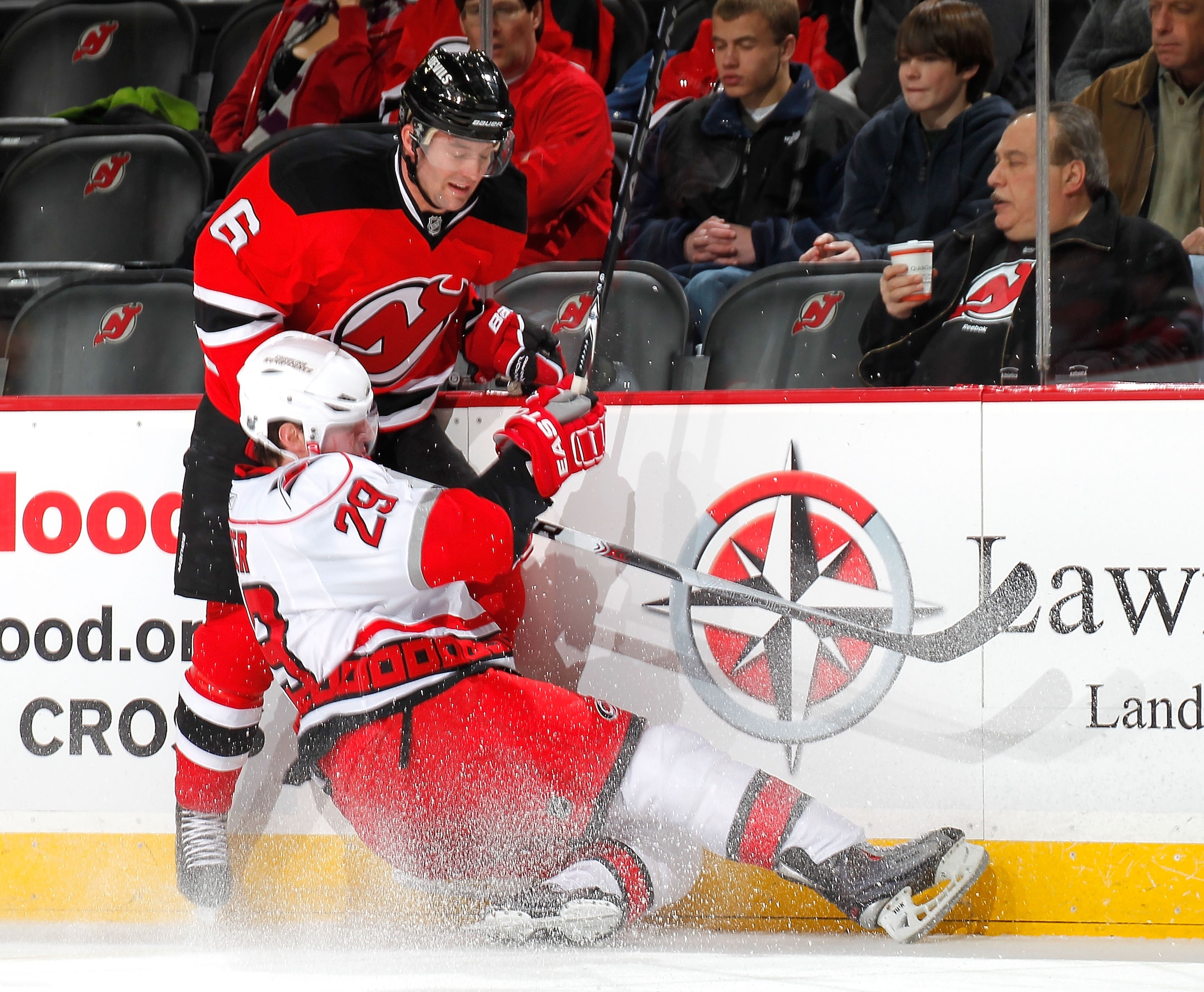 NEWARK, NJ - FEBRUARY 08:  Ryan Carter #29 of the Carolina Hurricanes goes down as he checked Andy Greene #6 of the New Jersey Devils during the first period of an NHL hockey game at the Prudential Center on February 8, 2011 in Newark, New Jersey.  (Photo