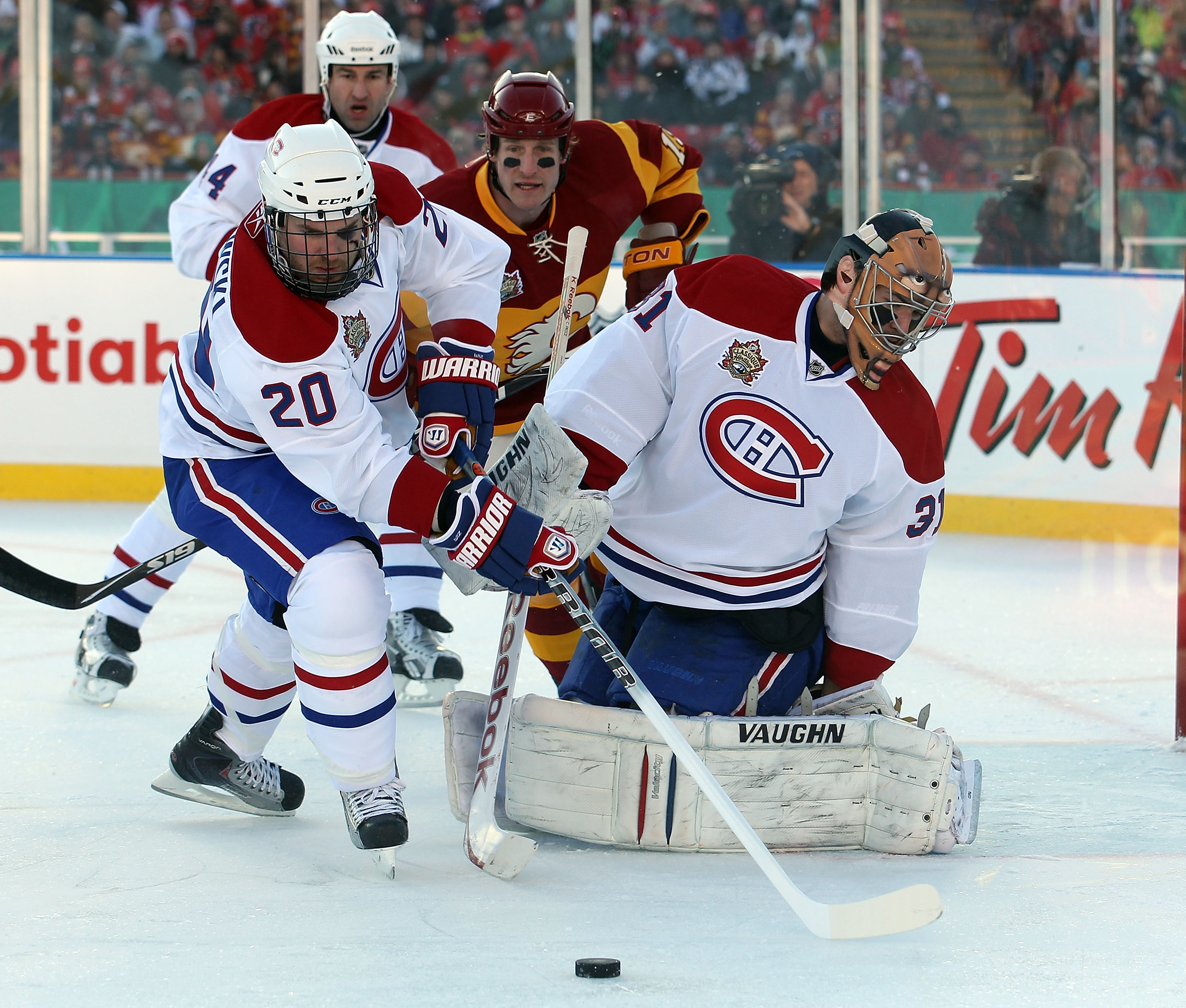CALGARY, AB - FEBRUARY 20: James Wisniewski #20 of the Montreal Canadiens moves the puck in front of Carey Price #31 and away from Tim Jackman #15 of the Calgary Flames during the 2011 NHL Heritage Classic Game at McMahon Stadium on February 20, 2011 in C