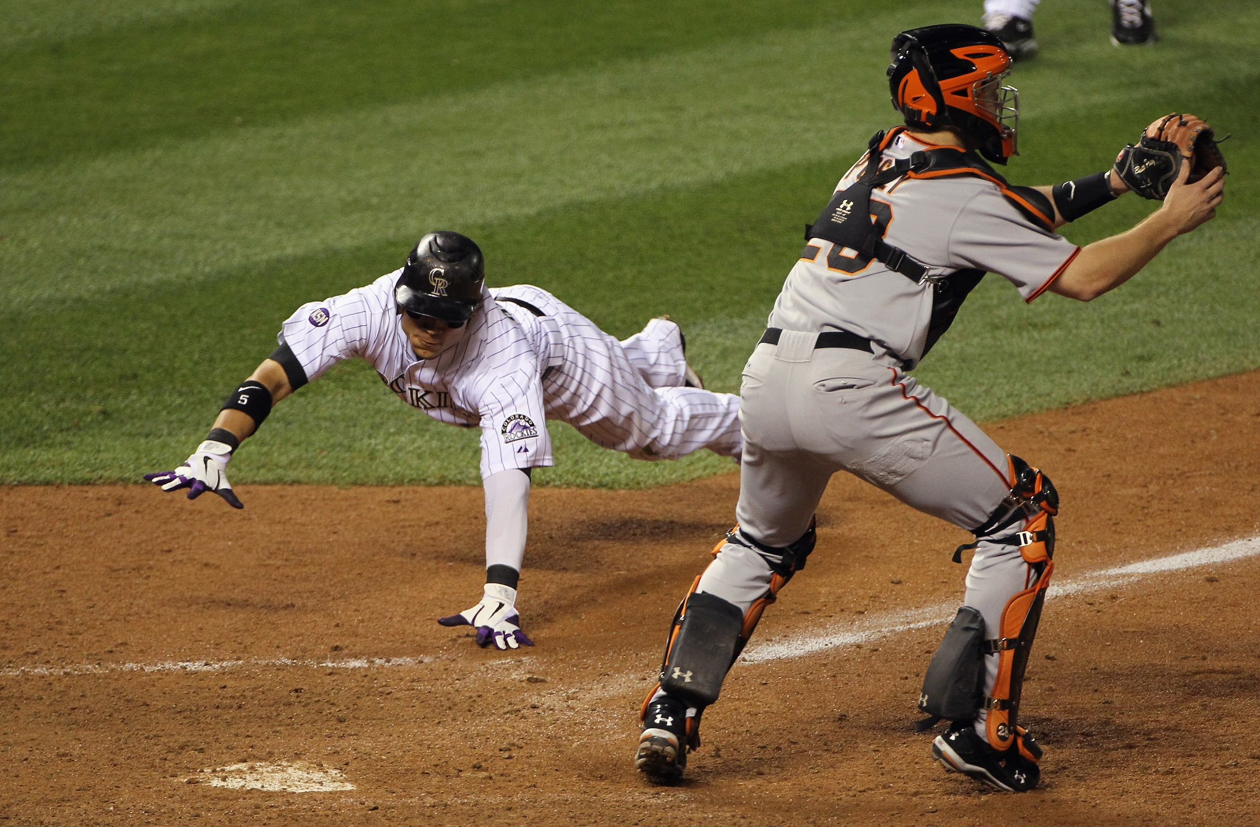 DENVER - SEPTEMBER 25:  Carlos Gonzalez #5 of the Colorado Rockies dives home to score the game winning run behind catcher Buster Posey #28 of the San Francisco Giants on a double by Troy Tulowitzki off of relief pitcher Brian Wilson of the Giants in the