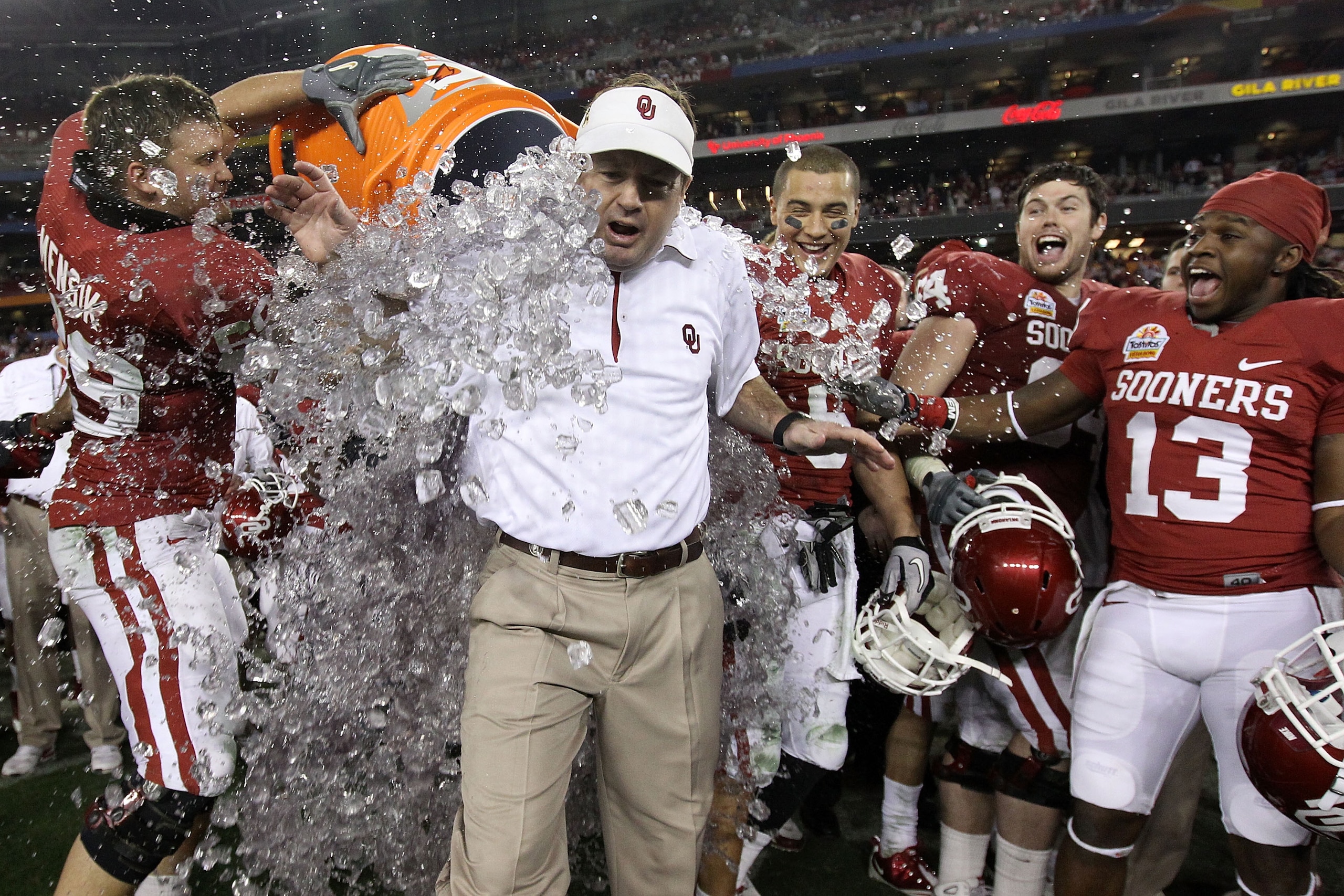 GLENDALE, AZ - JANUARY 01: Head coach Bob Stoops has a Gatorade bucket dumped on him by Eric Mensik #69 late in the fourth quarter before the Sooners 48-20 victory against the Connecticut Huskies during the Tostitos Fiesta Bowl at the Universtity of Phoe GLENDALE, AZ - JANUARY 01: Head coach Bob Stoops has a Gatorade bucket dumped on him by Eric Mensik #69 late in the fourth quarter before the Sooners 48-20 victory against the Connecticut Huskies during the Tostitos Fiesta Bowl at the Universtity of Phoe