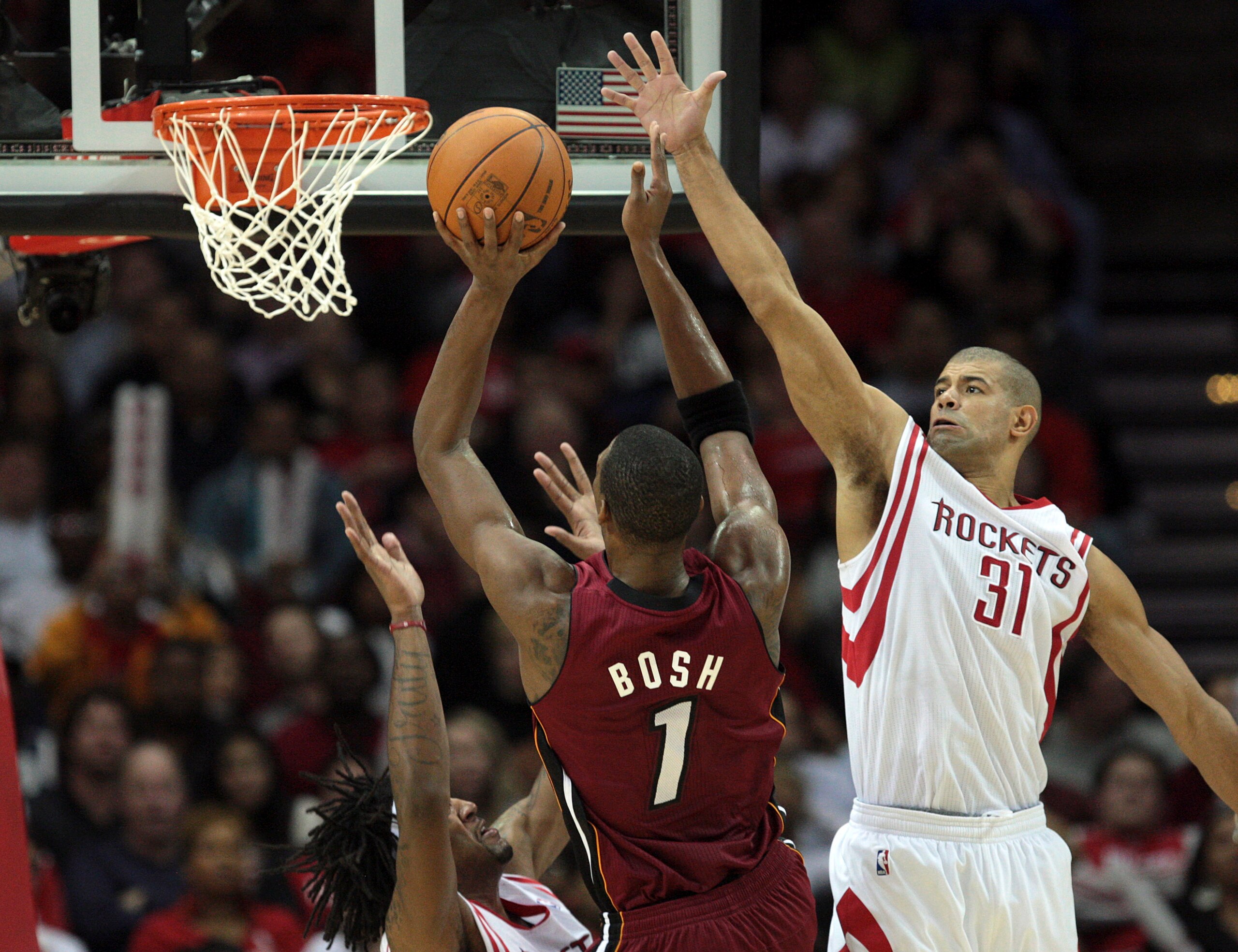 HOUSTON - DECEMBER 29: Chris Bosh #1 of the Miami Heat shoots over Shane Battier #31 of the Houston Rockets and Jordan Hill, left, in the fourth quarter at Toyota Center on December 29, 2010 in Houston, Texas. Miami won 125-119. NOTE TO USER: User express