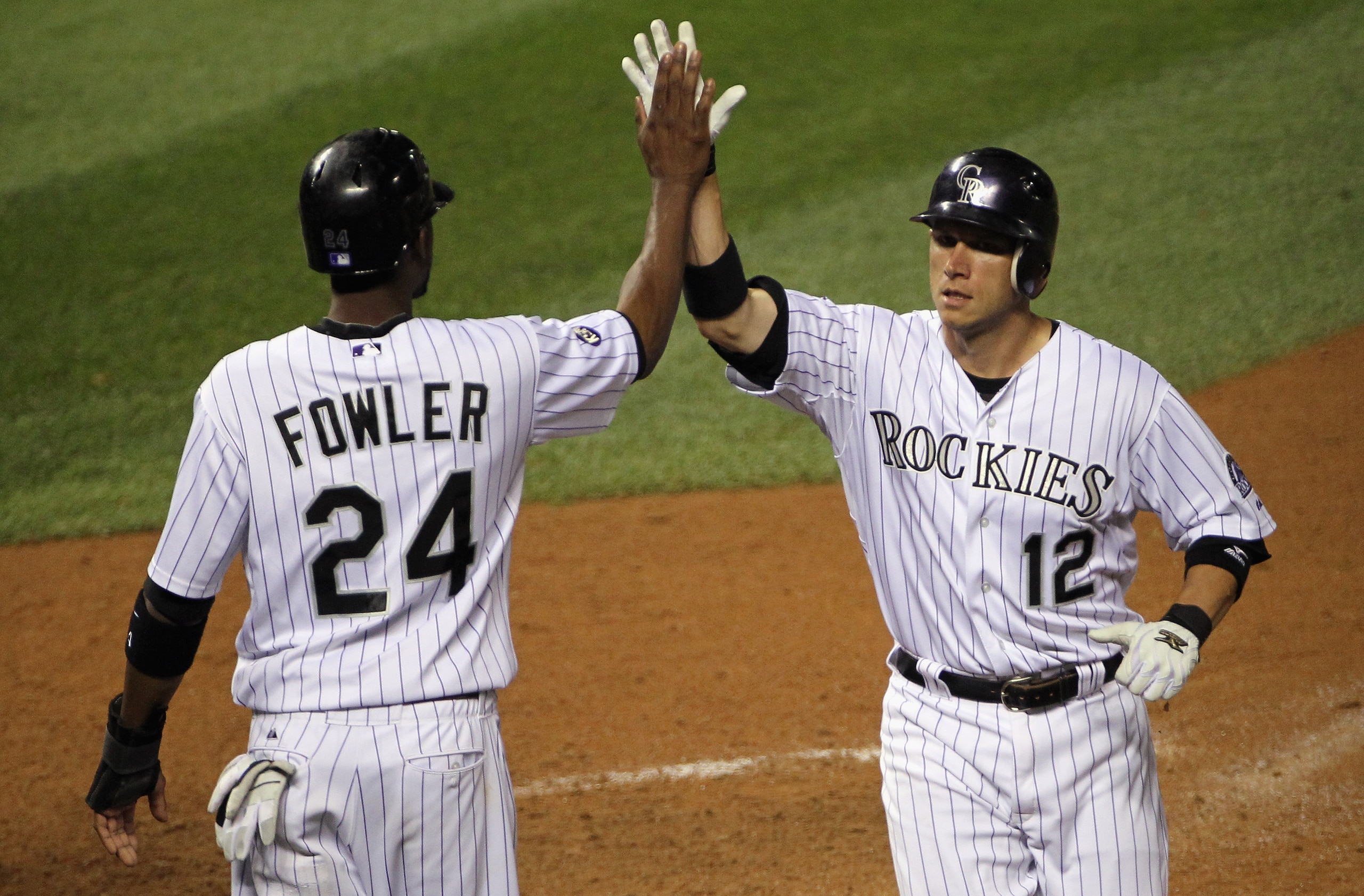 DENVER - SEPTEMBER 25:  Clint Barmes #12 and Dexter Fowler #24 of the Colorado Rockies celebrate after they scored on a double by Troy Tulowitzki to tie the score 9-9 with the San Francisco Giants in the eighth inning at Coors Field on September 25, 2010 