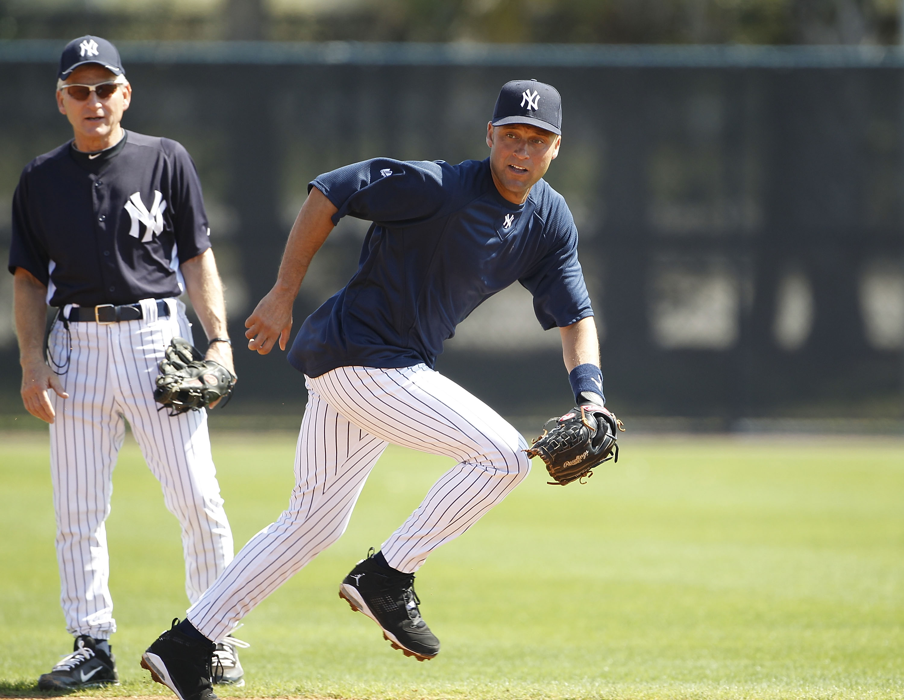 TAMPA, FL - FEBRUARY 21:  Derek Jeter #2 of the New York Yankees breaks for a ground ball as Mick Kelleher #50 looks on during the second day of full teams workouts at Spring Training on February 21, 2011 at the George M. Steinbrenner Field in Tampa, Flor