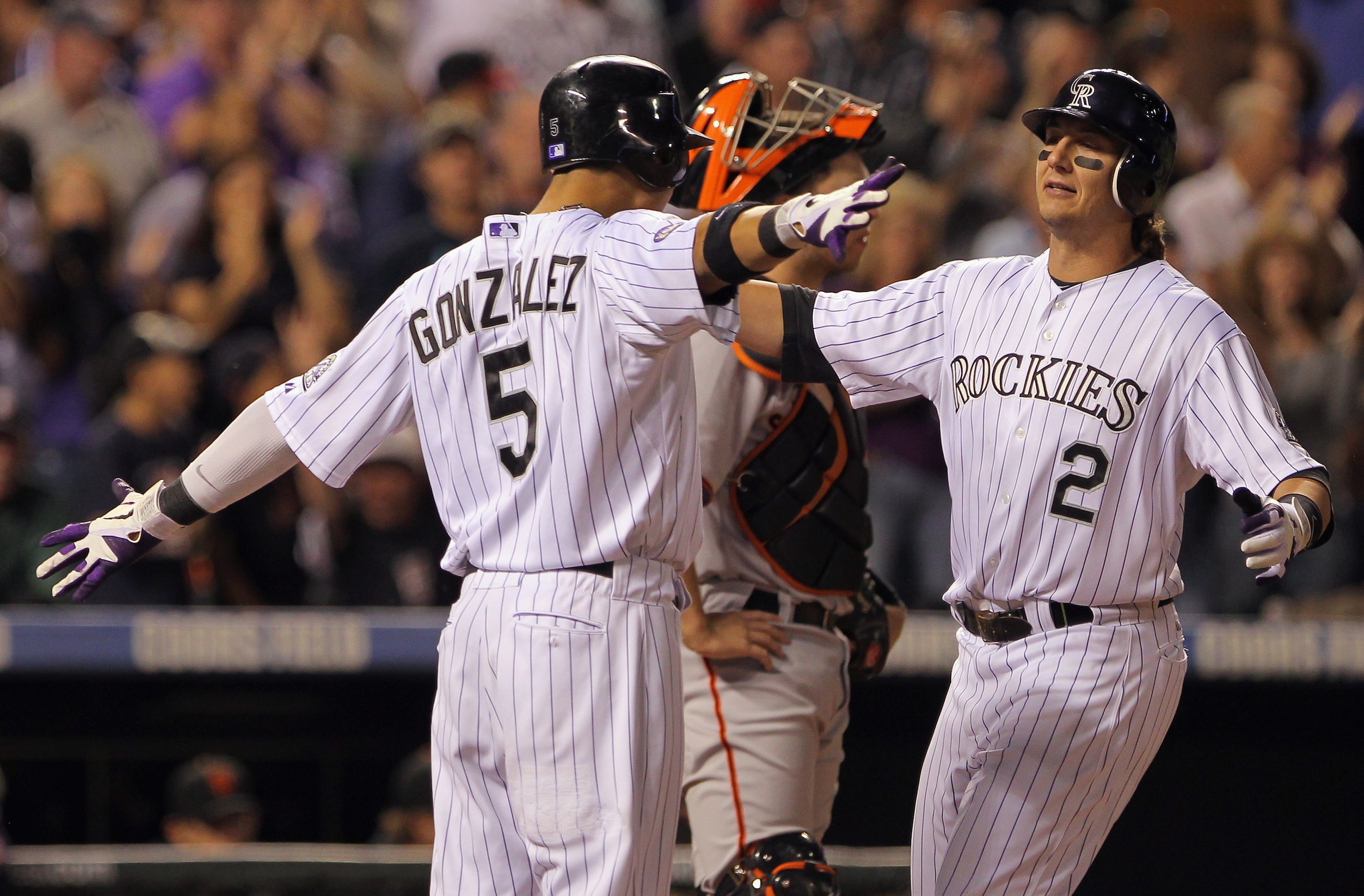 DENVER - SEPTEMBER 25:  Troy Tulowitzki #2 of the Colorado Rockies is welcomed home by Carlos Gonzalez #5 who scored on his two run homerun to give the Rockies a 5-4 lead over the San Francisco Giants in the fifth inning at Coors Field on September 25, 20