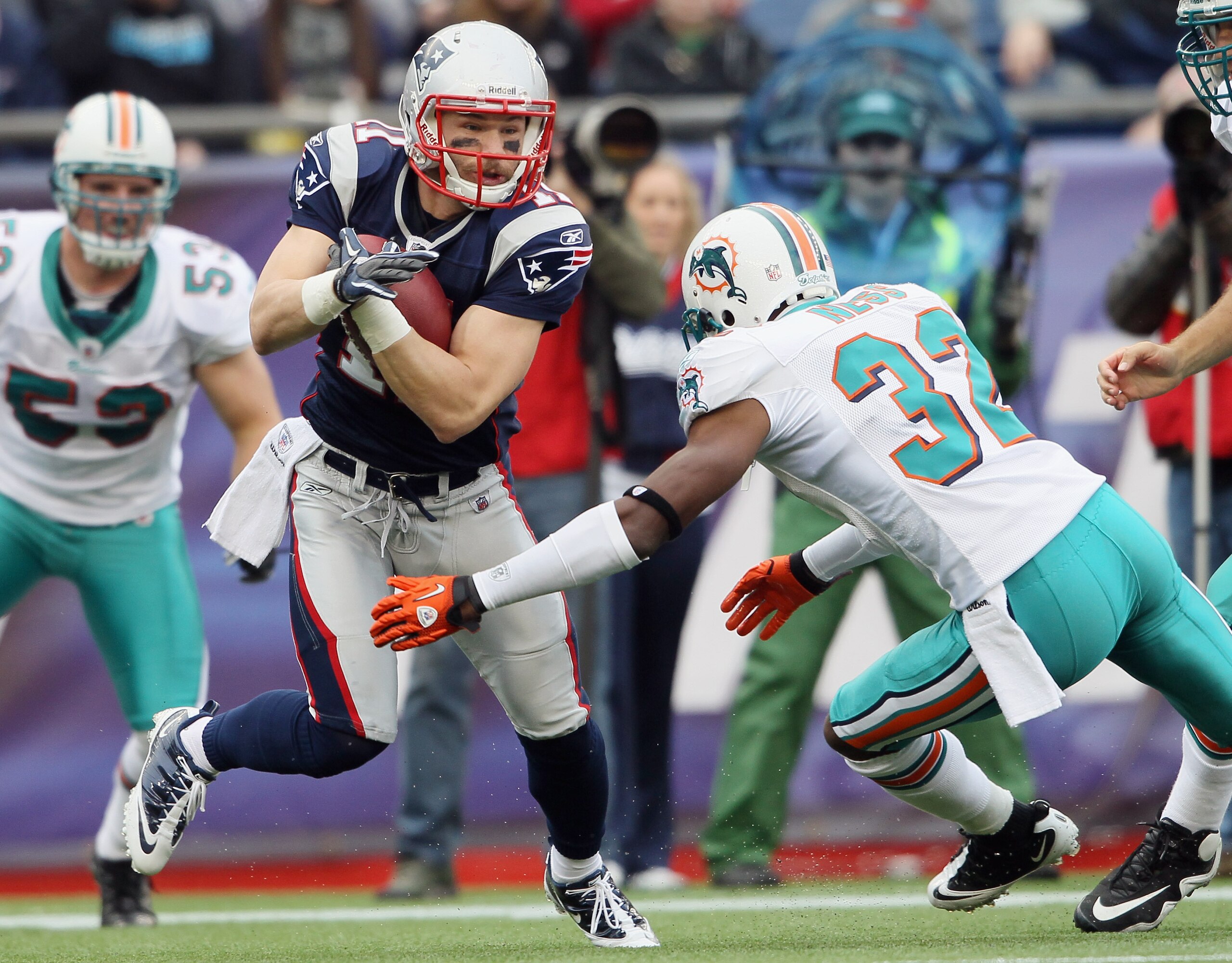 FOXBORO, MA - JANUARY 02:  Julian Edelman #11 of the New England Patriots carries the ball as Nate Ness #32 of the Miami Dolphins defends on January 2, 2011 at Gillette Stadium in Foxboro, Massachusetts.  (Photo by Elsa/Getty Images)
