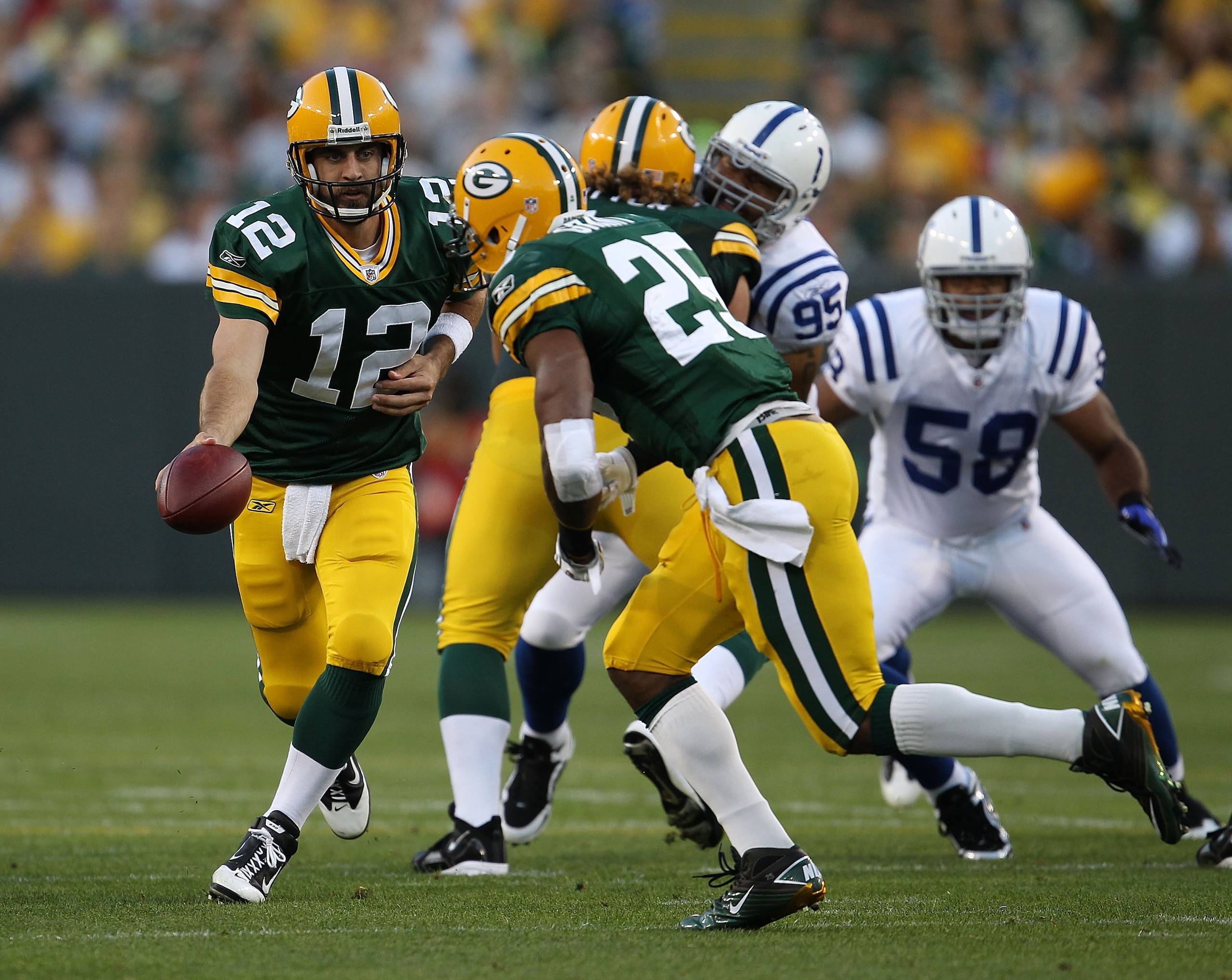 GREEN BAY, WI - AUGUST 26: Aaron Rodgers #12 of the Green Bay Packers turns to hand off to Ryan Grant #25 against the Indianapolis Colts during a preseason game at Lambeau Field on August 26, 2010 in Green Bay, Wisconsin. The Packers defeated the Colts 59