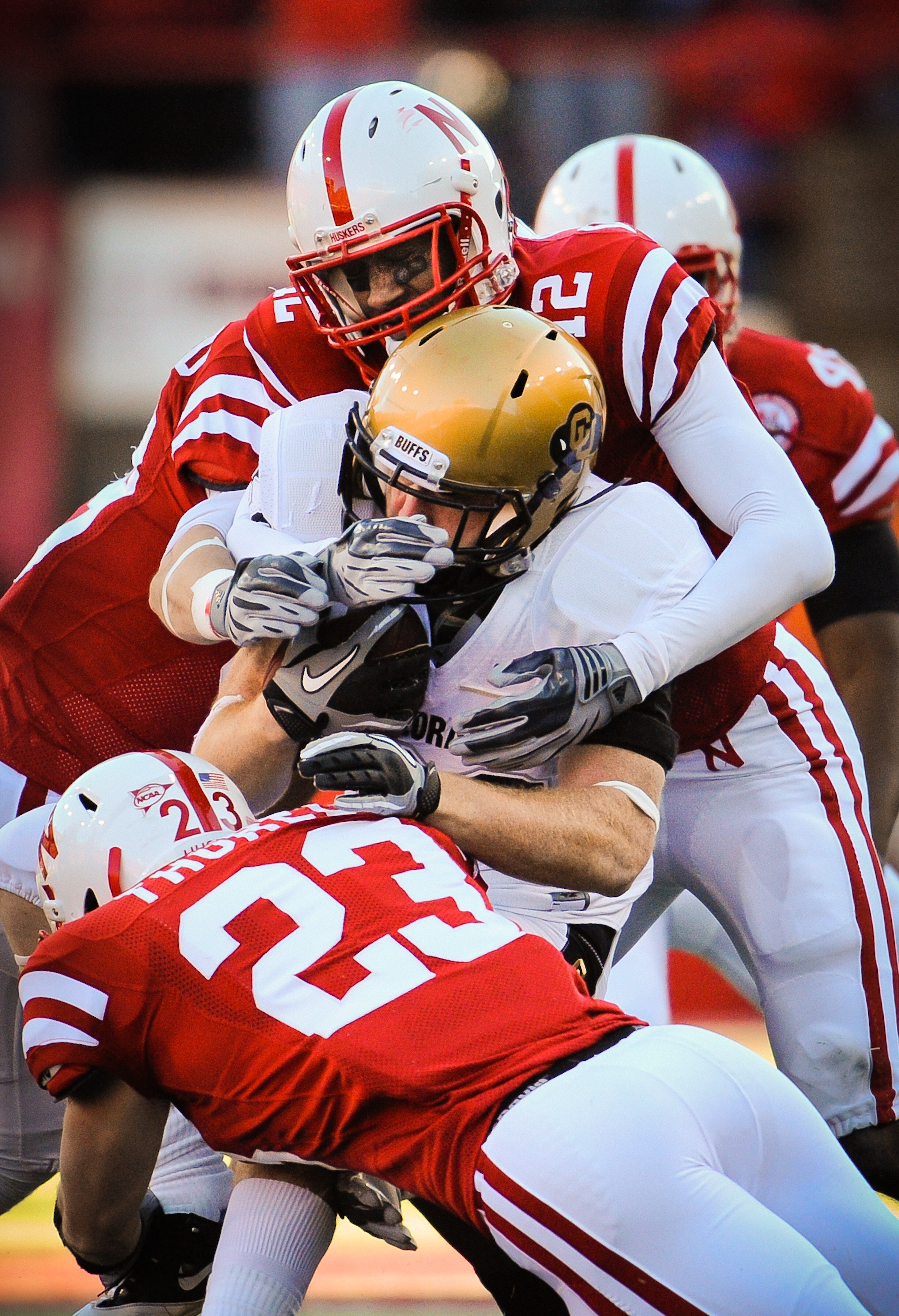 LINCOLN, NE - NOVEMBER 26: Courtney Osborne #12 and Lance Thorell #23 of the Nebraska Cornhuskers wrap up Parke Robbins #22 of the Colorado Buffaloes during their game at Memorial Stadium on November 26, 2010 in Lincoln, Nebraska. Nebraska defeated Colora