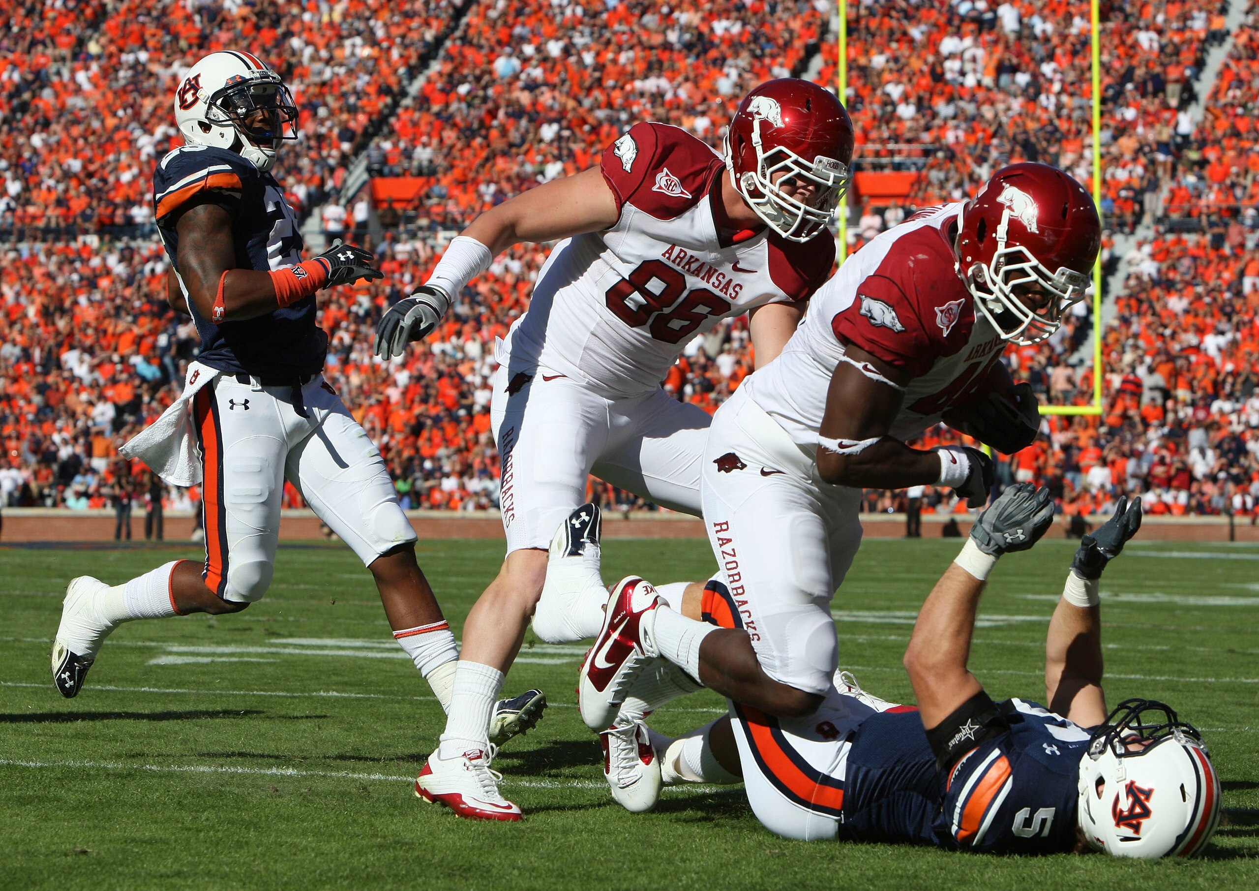 AUBURN - OCTOBER 16: Fullback Van Stumon #44 of the Arkansas Razorbacks (second from right) runs over linebacker Jake Holland #5 of the Auburn Tigers (on the ground) while tight end Garrett Uekman #88 of the Arkansas Razorbacks (center) looks on during t AUBURN - OCTOBER 16: Fullback Van Stumon #44 of the Arkansas Razorbacks (second from right) runs over linebacker Jake Holland #5 of the Auburn Tigers (on the ground) while tight end Garrett Uekman #88 of the Arkansas Razorbacks (center) looks on during t