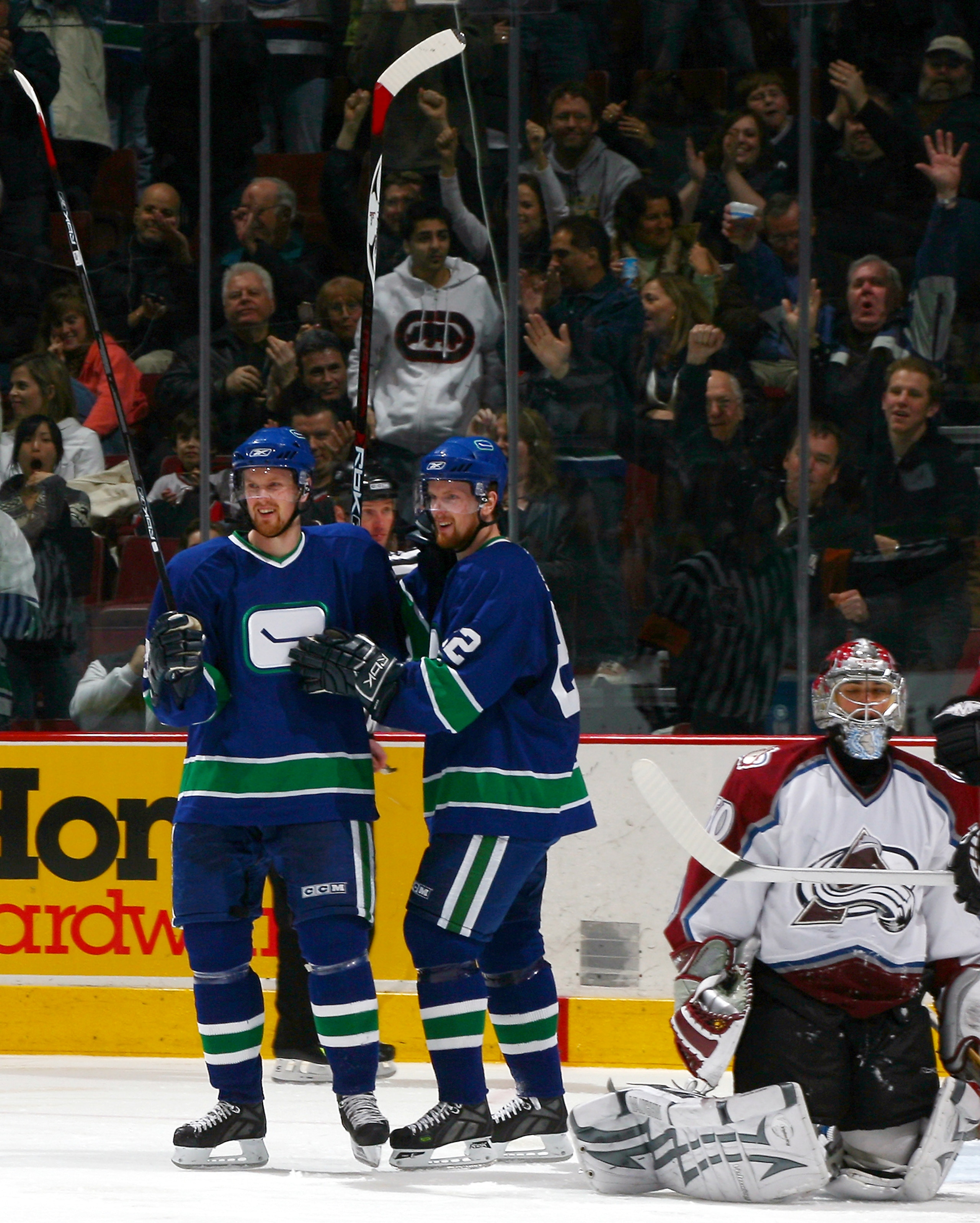 VANCOUVER, CANADA - FEBRUARY 18:   Henrik Sedin #33 (left) and Daniel Sedin #22 of the Vancouver Canucks celebrate Henrik's goal as Jose Theodore #60 of the Colorado Avalanche sits alongside in the crease during their game at General Motors Place on Febru