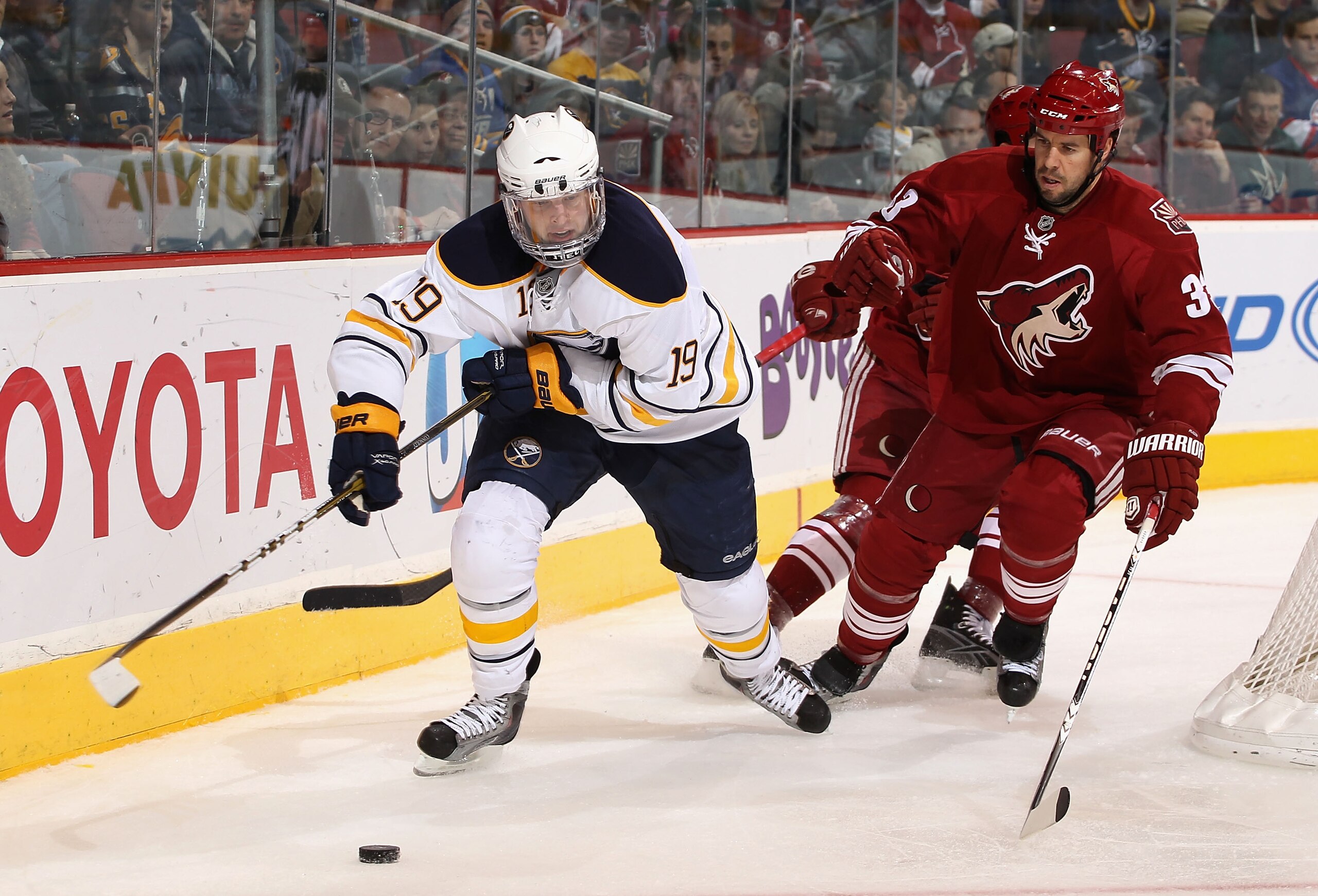 GLENDALE, AZ - JANUARY 08:  Tim Connolly #19 of the Buffalo Sabres skates with the puck past Adrian Aucoin #33 of the Phoenix Coyotes during the NHL game at Jobing.com Arena on January 8, 2011 in Glendale, Arizona.  The Sabres defeated the Coyotes 2-1 in