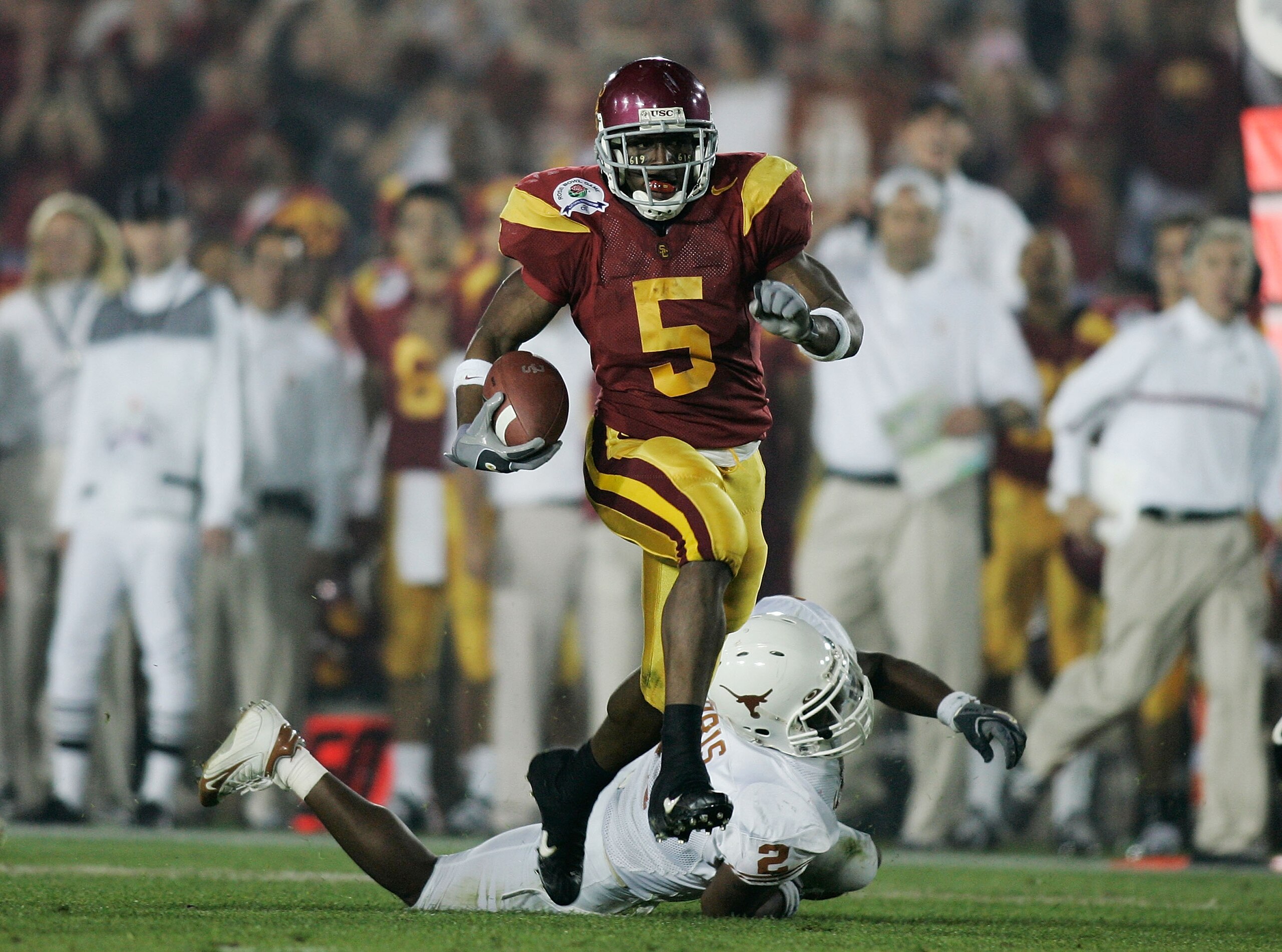 PASADENA, CA - JANUARY 04:  Running back Reggie Bush #5 of the USC Trojans carries the football past Aaron Harris #2 of the Texas Longhorns before fumbling the ball on the play in the second quarter during the BCS National Championship Rose Bowl Game on J