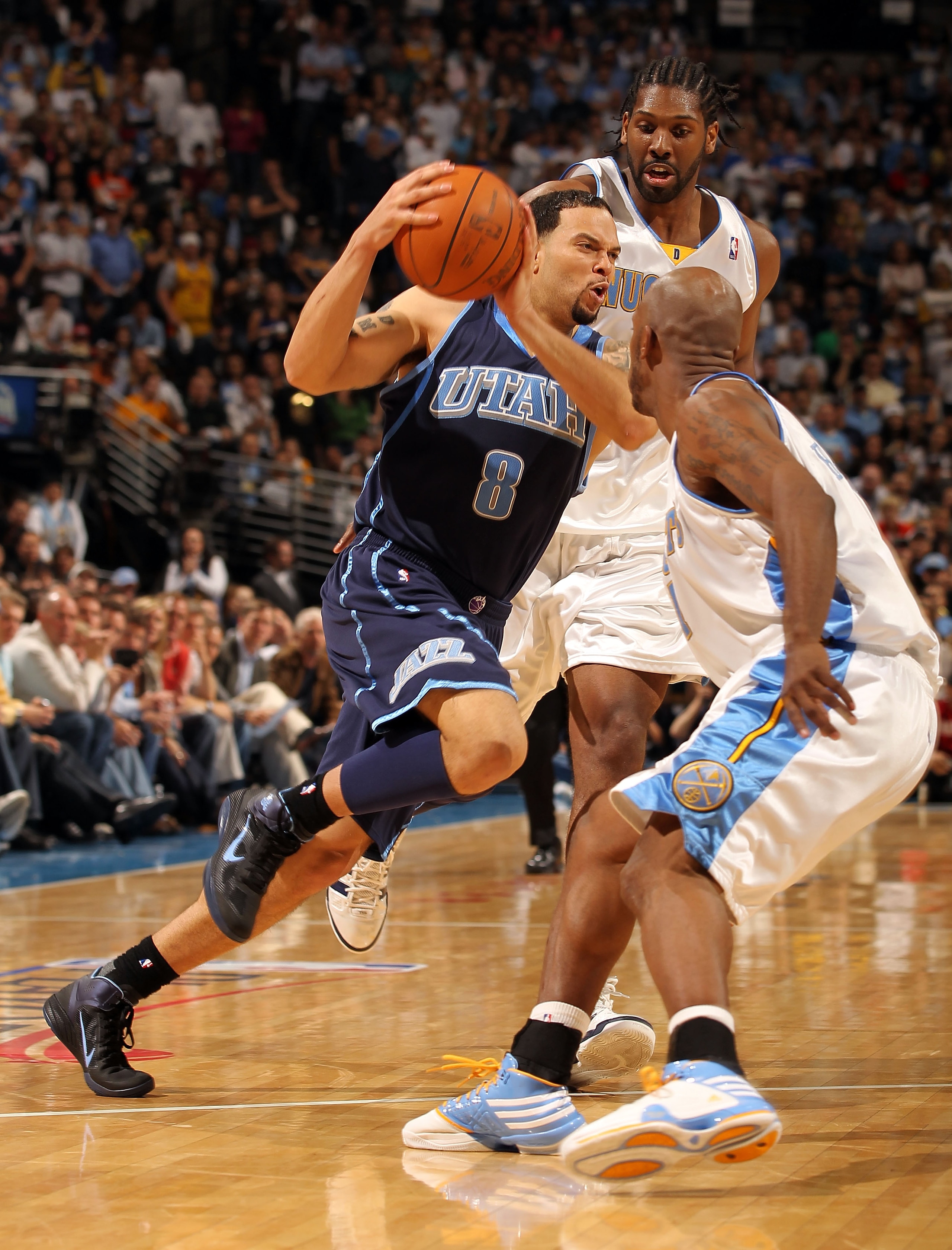 DENVER - APRIL 19: Deron Williams #8 of the Utah Jazz drives between Nene #31 and Chauncey Billups #1 of the Denver Nuggets in Game Two of the NBA Western Conference Quarterfinals at the Pepsi Center on April 19, 2010 in Denver, Colorado. Williams had a DENVER - APRIL 19: Deron Williams #8 of the Utah Jazz drives between Nene #31 and Chauncey Billups #1 of the Denver Nuggets in Game Two of the NBA Western Conference Quarterfinals at the Pepsi Center on April 19, 2010 in Denver, Colorado. Williams had a