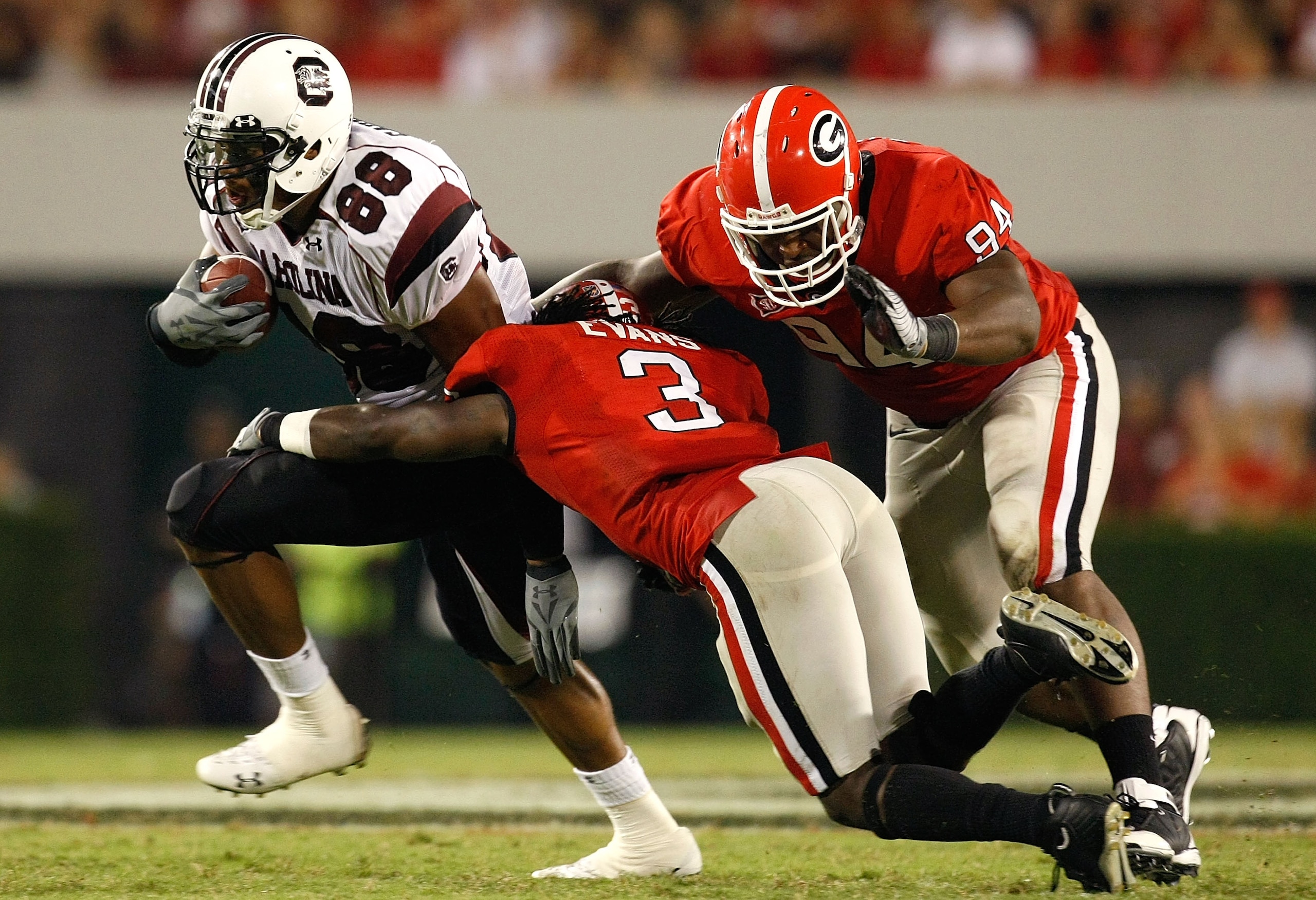 ATHENS, GA - SEPTEMBER 12:  Weslye Saunders #88 of the South Carolina Gamecocks breaks a tackle by Bryan Evans #3 and DeAngelo Tyson #94 of the Georgia Bulldogs at Sanford Stadium on September 12, 2009 in Athens, Georgia.  (Photo by Kevin C. Cox/Getty Ima