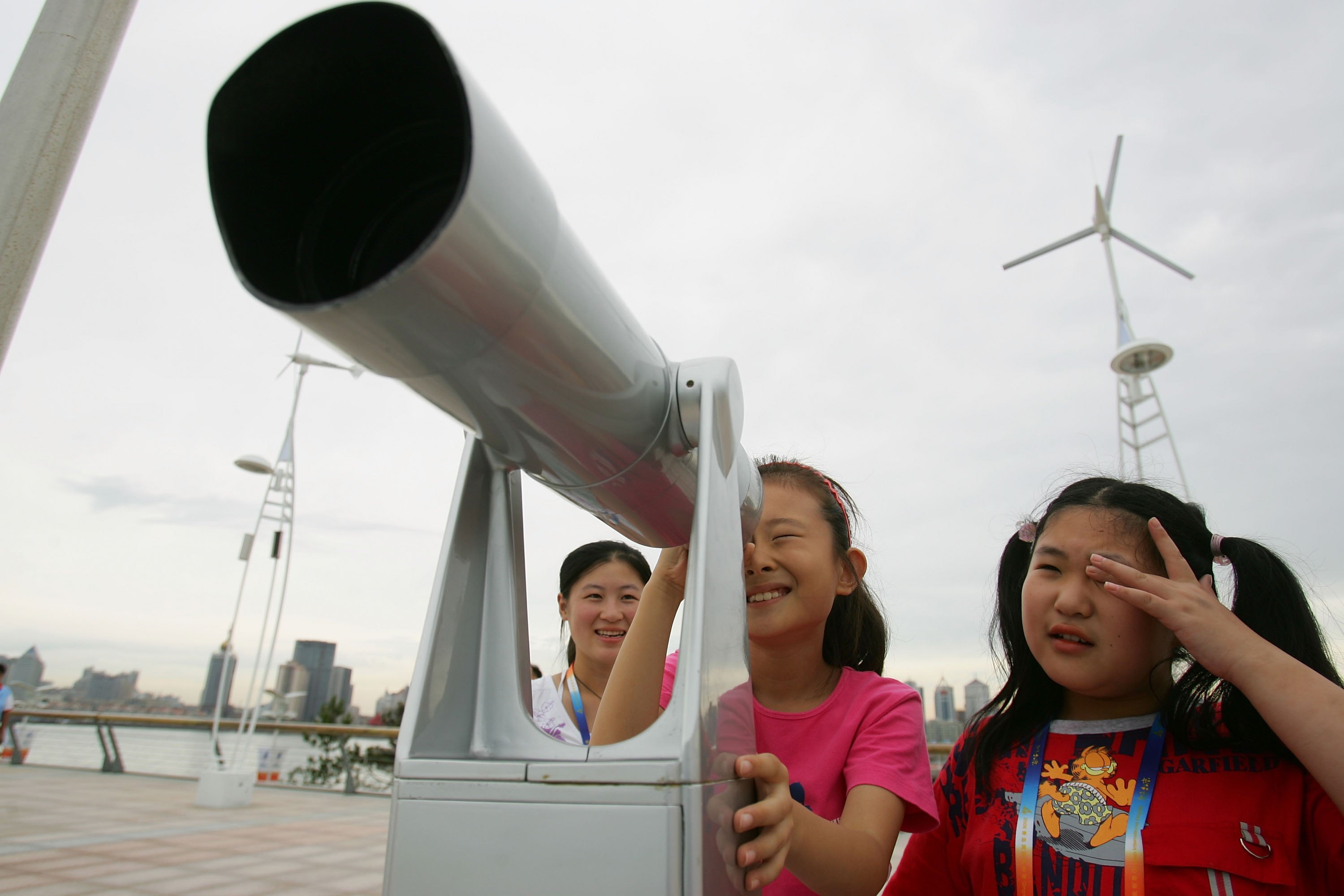 QINGDAO, SHANDONG - AUGUST 26:  Chinese children watch the competition with a telescope at the race observation area of the Qingdao Olympic Sailing Center during the 2006 Qingdao International Regatta, which is the first official test event for the 2008 B
