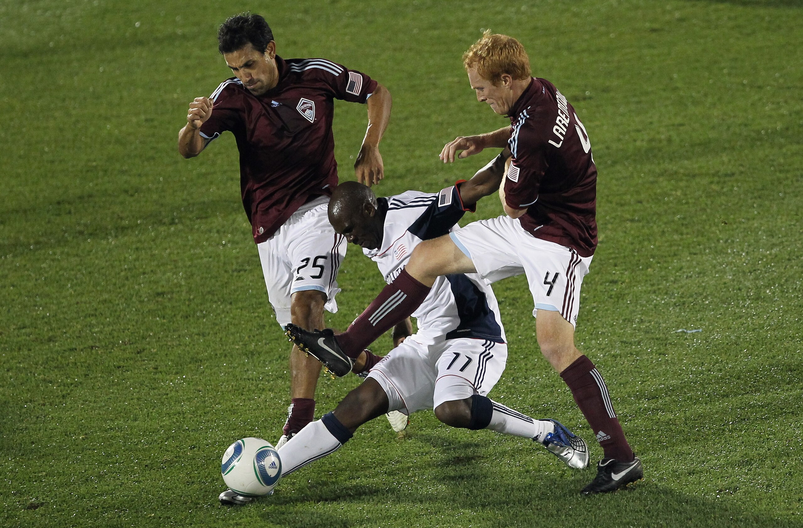COMMERCE CITY, CO - SEPTEMBER 18:  Kheli Dube #11 of the New England Revolution controls the ball while under pressure from Pablo Mastroeni #25 and Jeff Larentowicz #4 of the Colorado Rapids at Dick's Sporting Goods Park on September 18, 2010 in Commerce