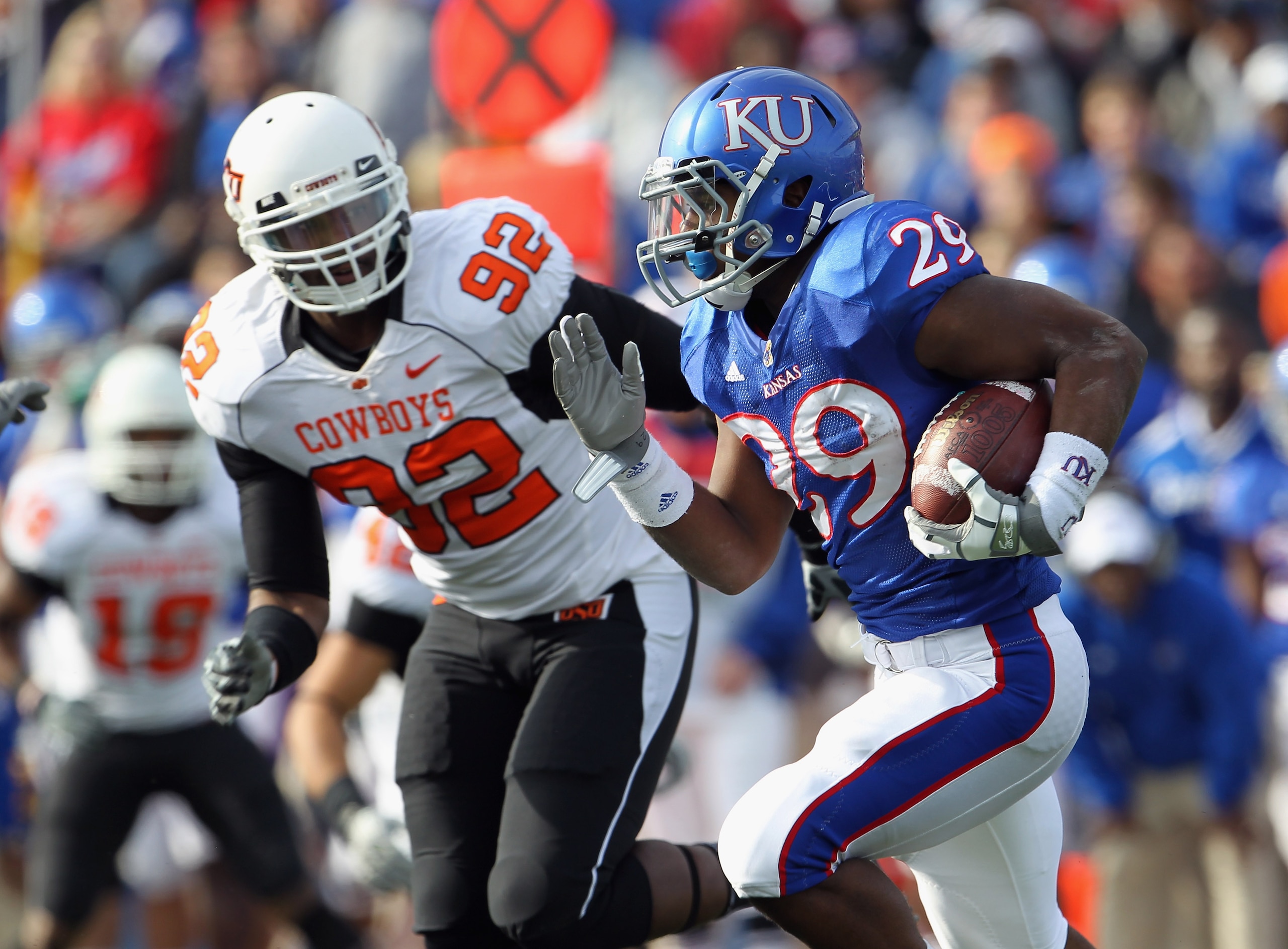 LAWRENCE, KS - NOVEMBER 20:  Running back James Sims #29 of the Kansas Jayhawks carries the ball as Darius Hart #92 of the Oklahoma State Cowboys defends during the game on November 20, 2010 at Memorial Stadium in Lawrence, Kansas.  (Photo by Jamie Squire