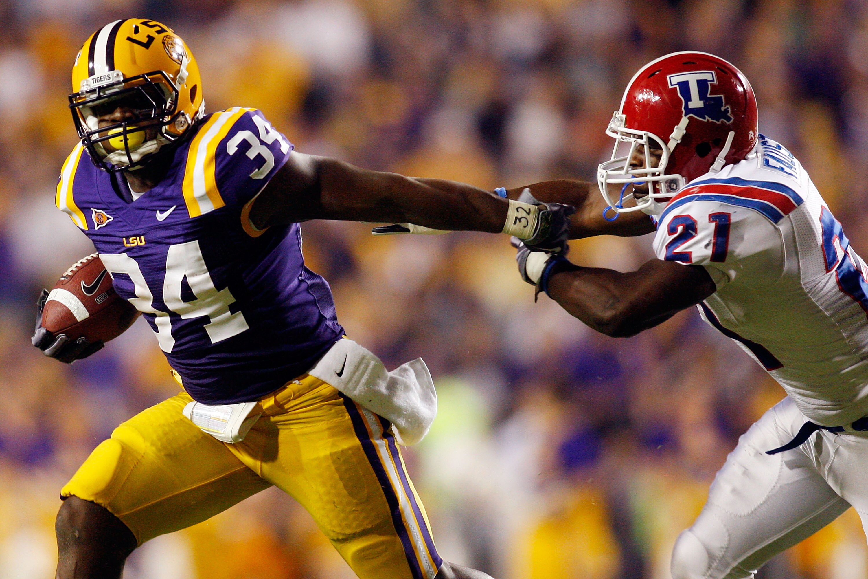BATON ROUGE, LA - NOVEMBER 14:  Stevan Ridley #34 of the LSU Tigers  avoids a tackle by Dominique Faust #21 of the Louisiana Tech Bulldogs at Tiger Stadium on November 14, 2009 in Baton Rouge, Louisiana.  The Tigers defeated the Bulldogs 24-16.  (Photo by