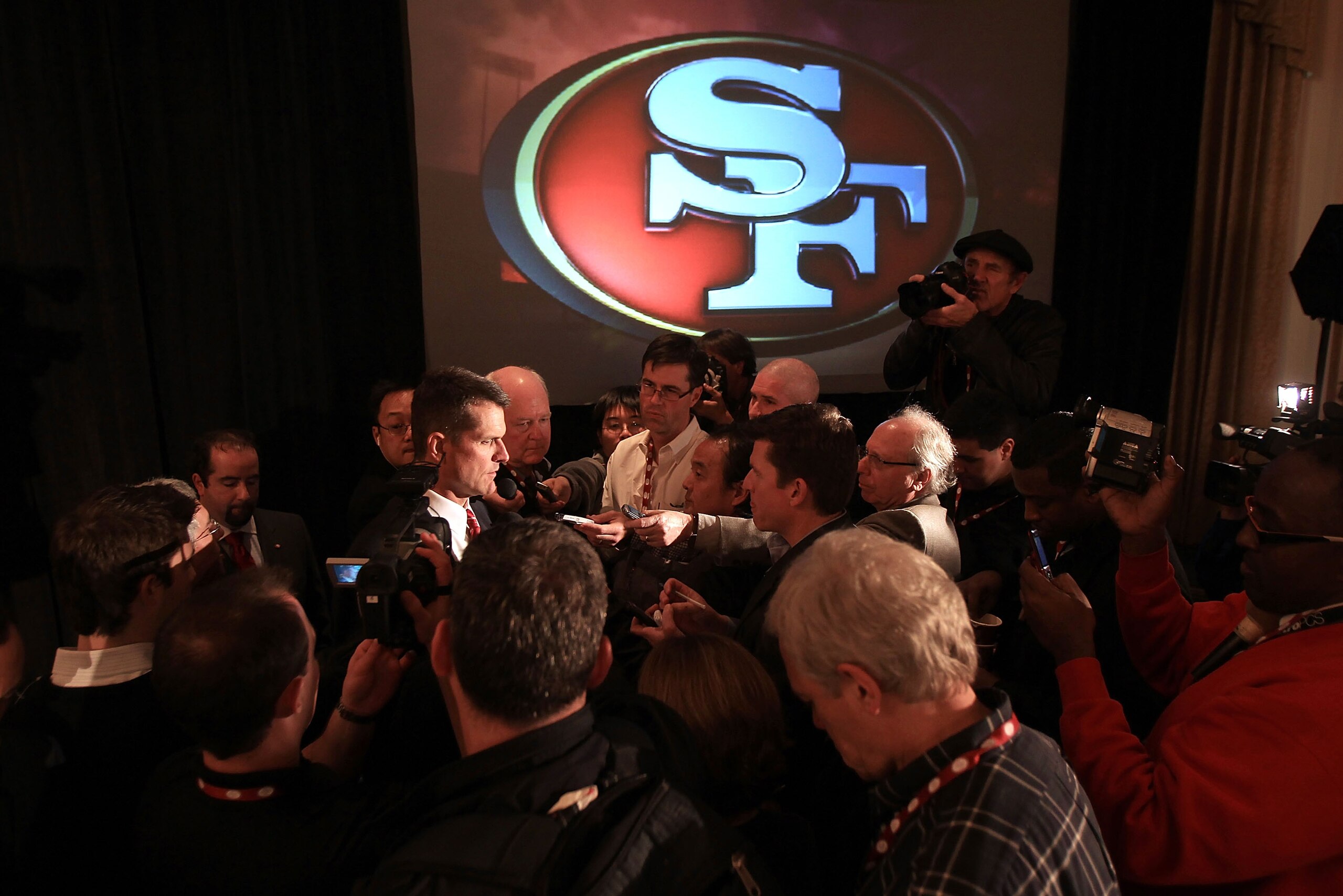 SAN FRANCISCO, CA - JANUARY 07:  Jim Harbaugh is surrounded by media following a press conference where he was introduced as the new San Francisco 49ers head coach at the Palace Hotel on January 7, 2011 in San Francisco, California.  (Photo by Ezra Shaw/G